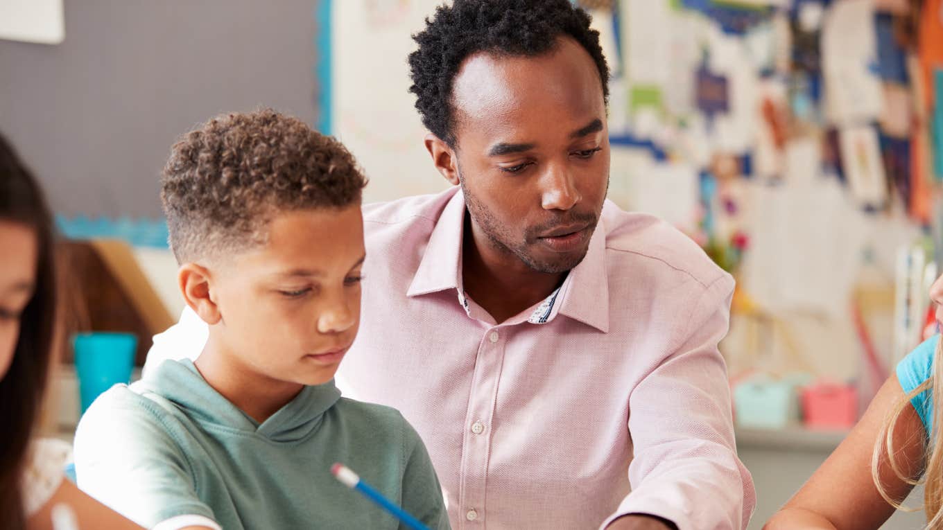 Middle school teacher helping student in class