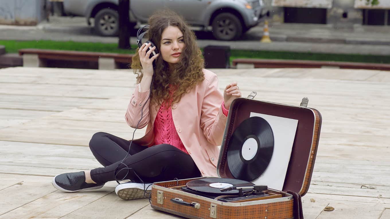 teenager sitting next to a record player listening to music