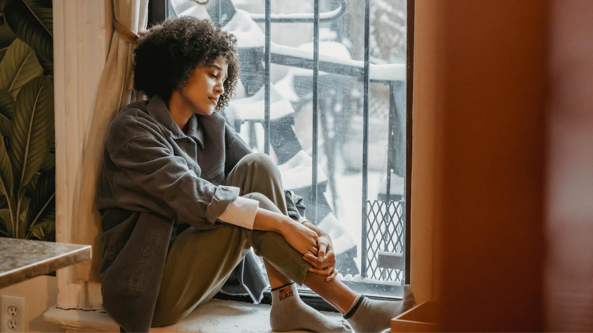 woman looking out the window in pain