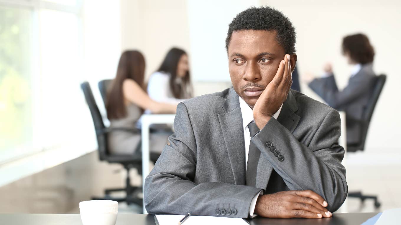 Employee in a suit ignoring co-workers behind him