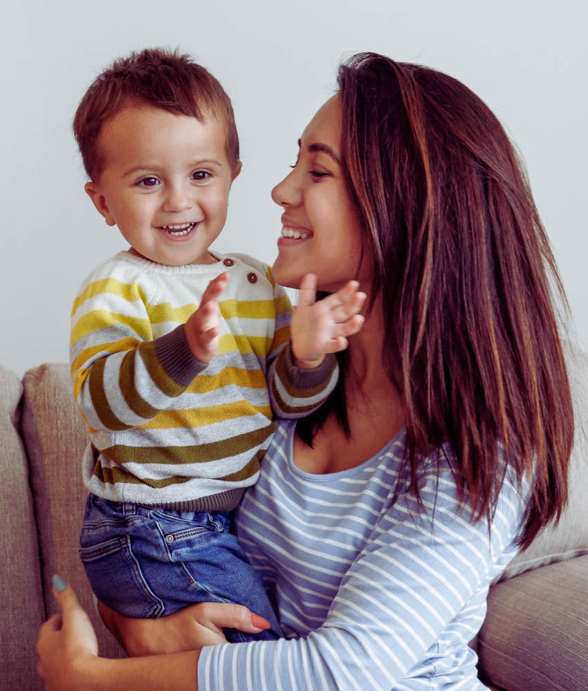 toddler clapping while mom holds him and smiles