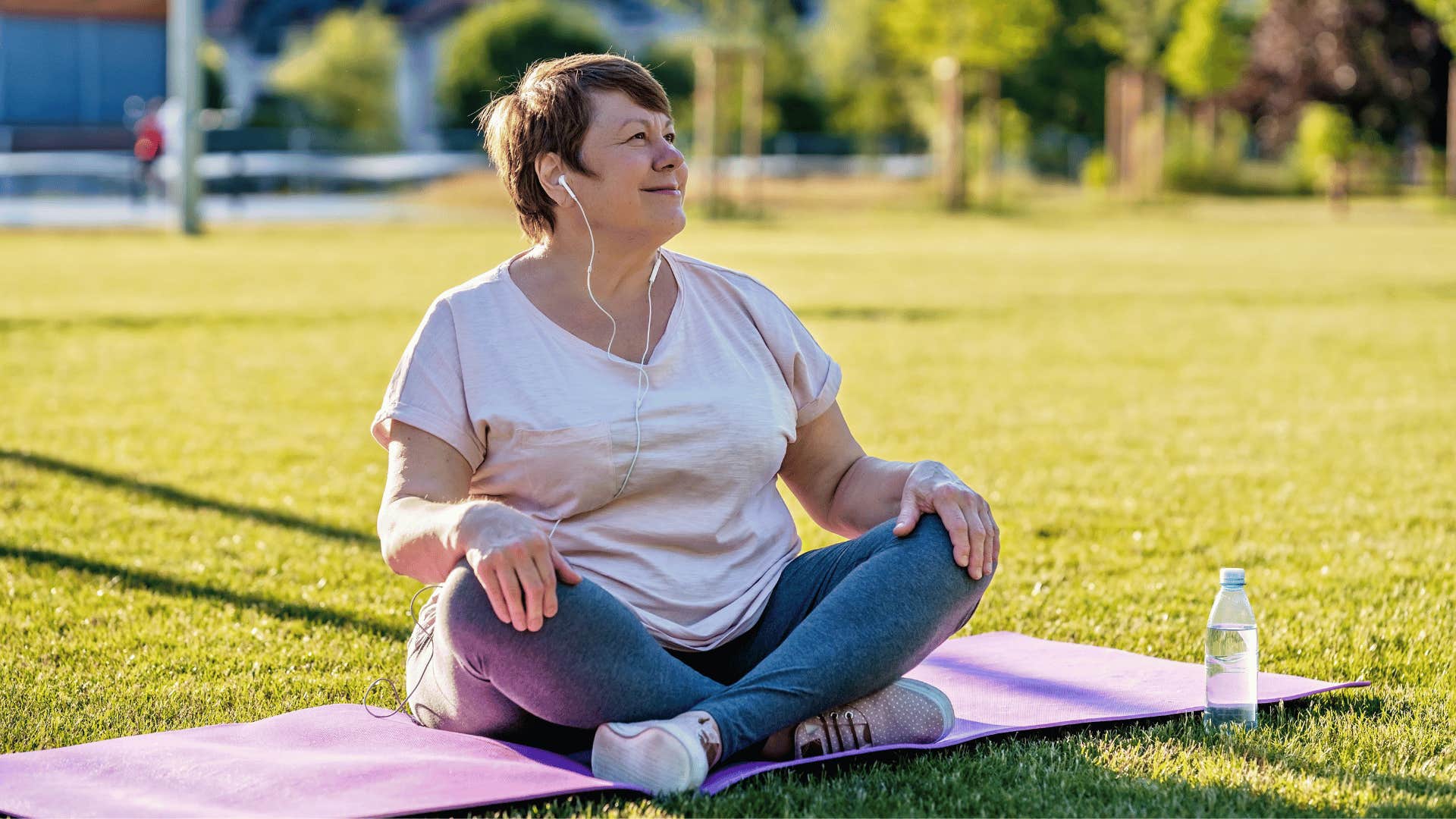 older woman exercising outside on yoga mat