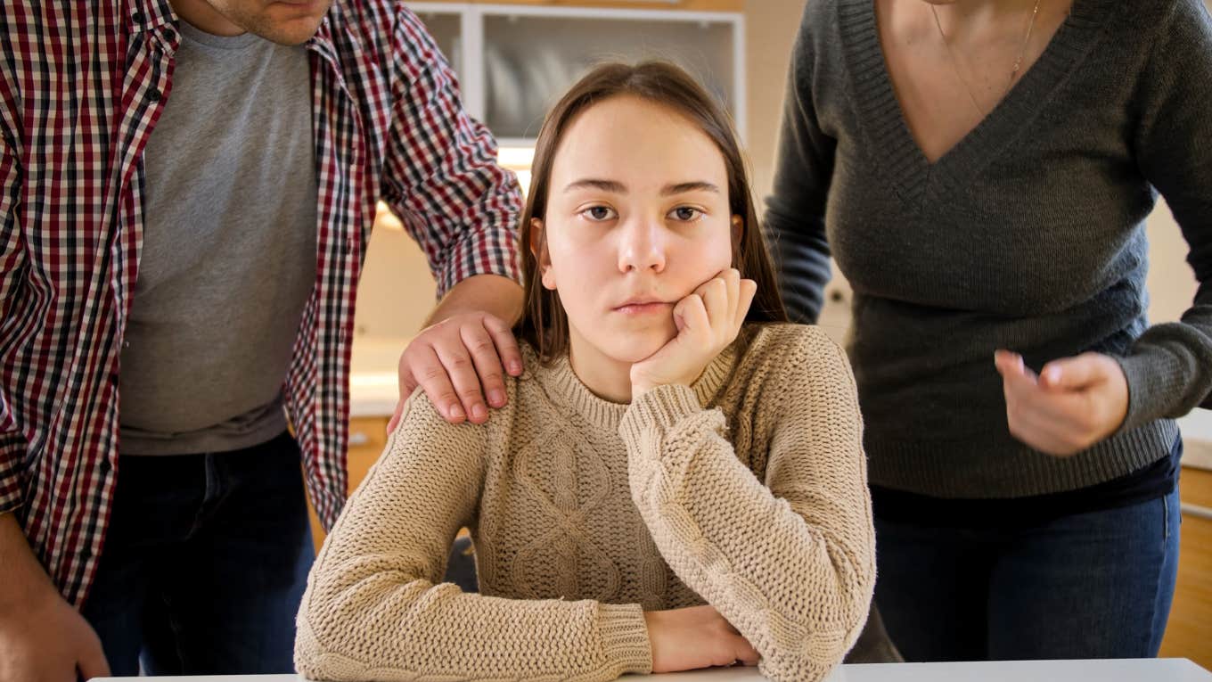 upset teen with parents fighting behind her