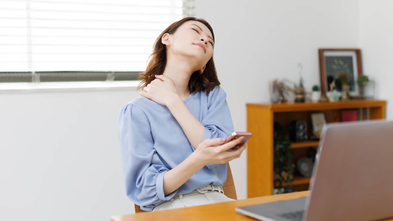 Woman sitting at desk holding her neck in pain