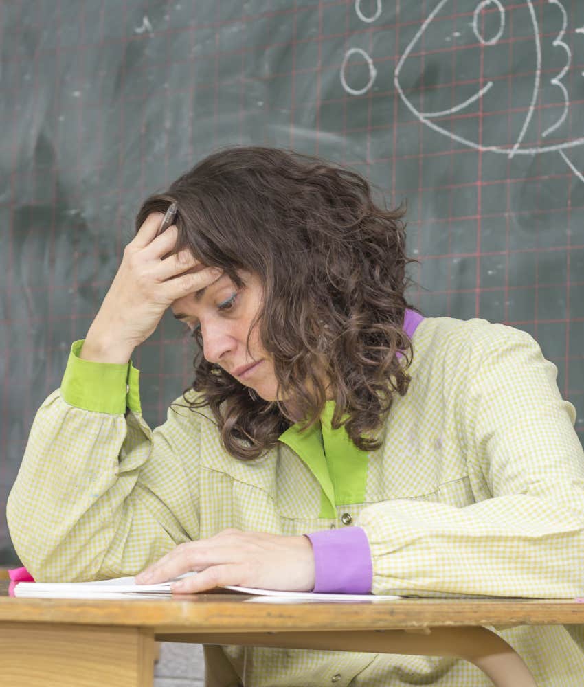 Frustrated teacher holding her head in her hand