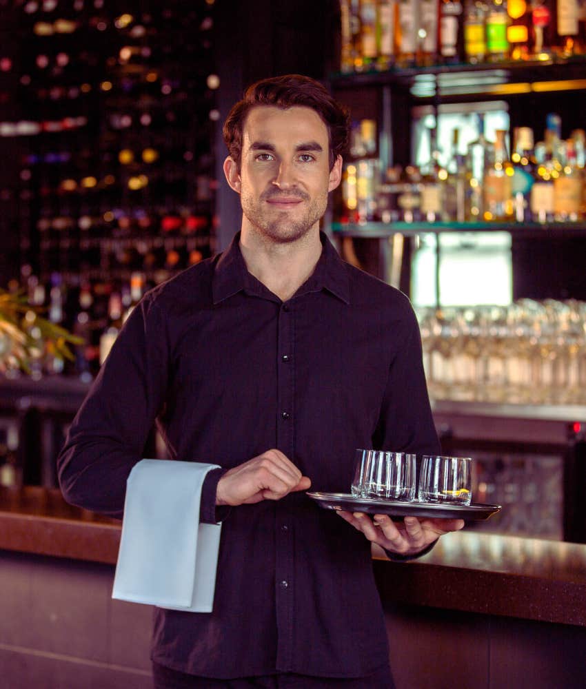 waiter holding a tray with a slight smile