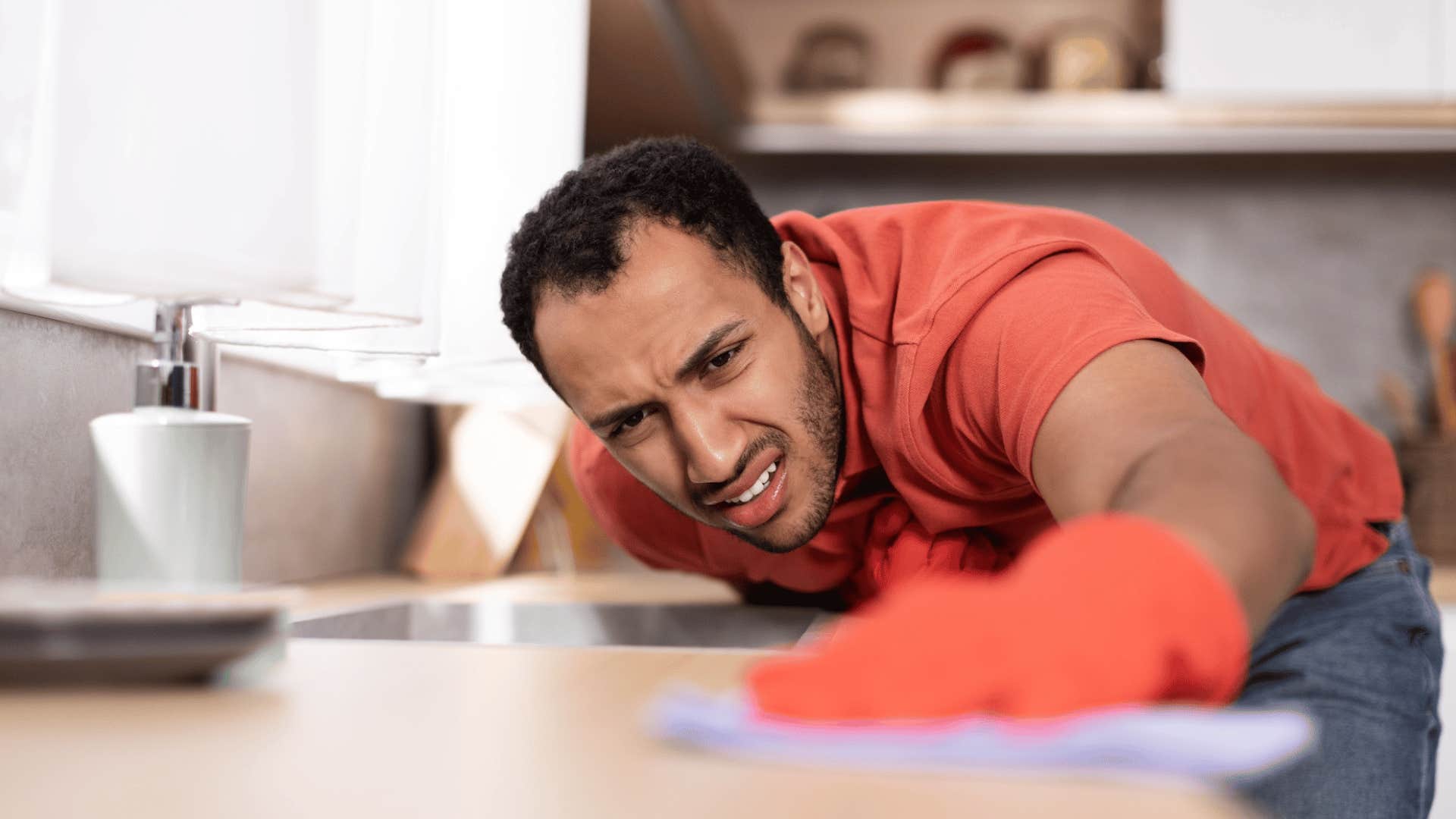 man meticulously cleaning kitchen counter