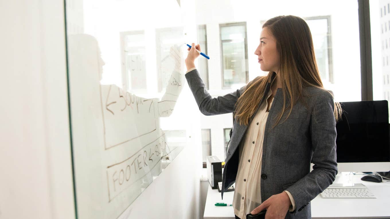 successful business woman writing on dry erase board