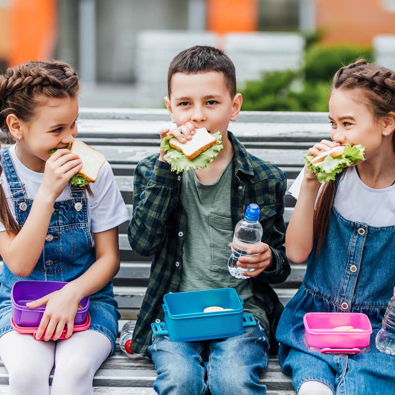 kids eating school lunch outside on bench