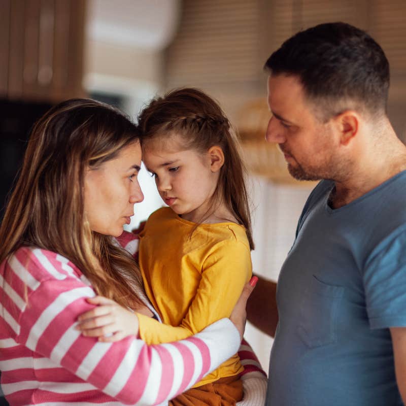 parents comforting upset little girl