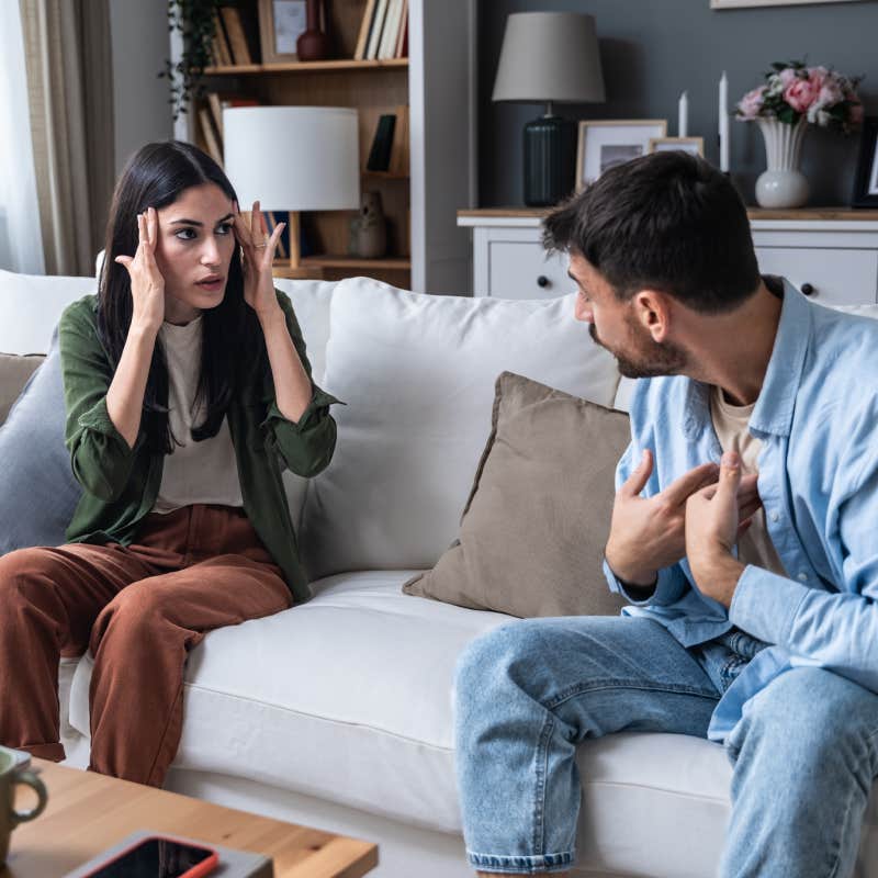 married couple arguing with each other on couch in living room