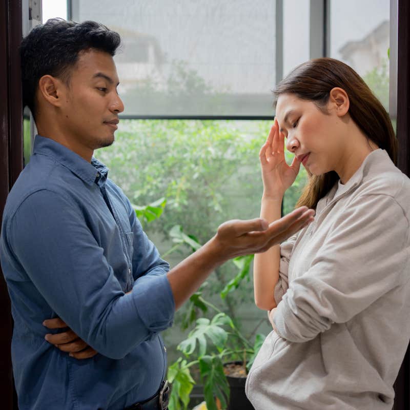 husband talking to frustrated wife in front of window at home