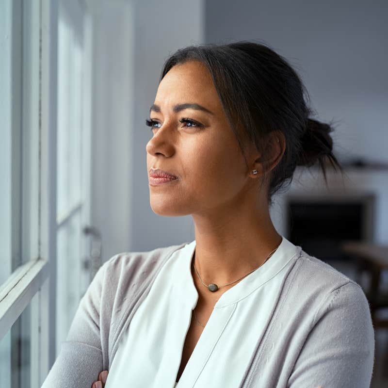 woman looking outside window with uncertainty