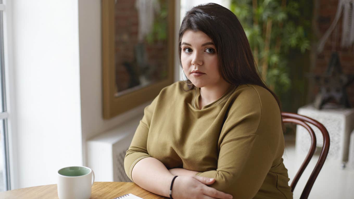 Sad woman sitting at table drinking coffee