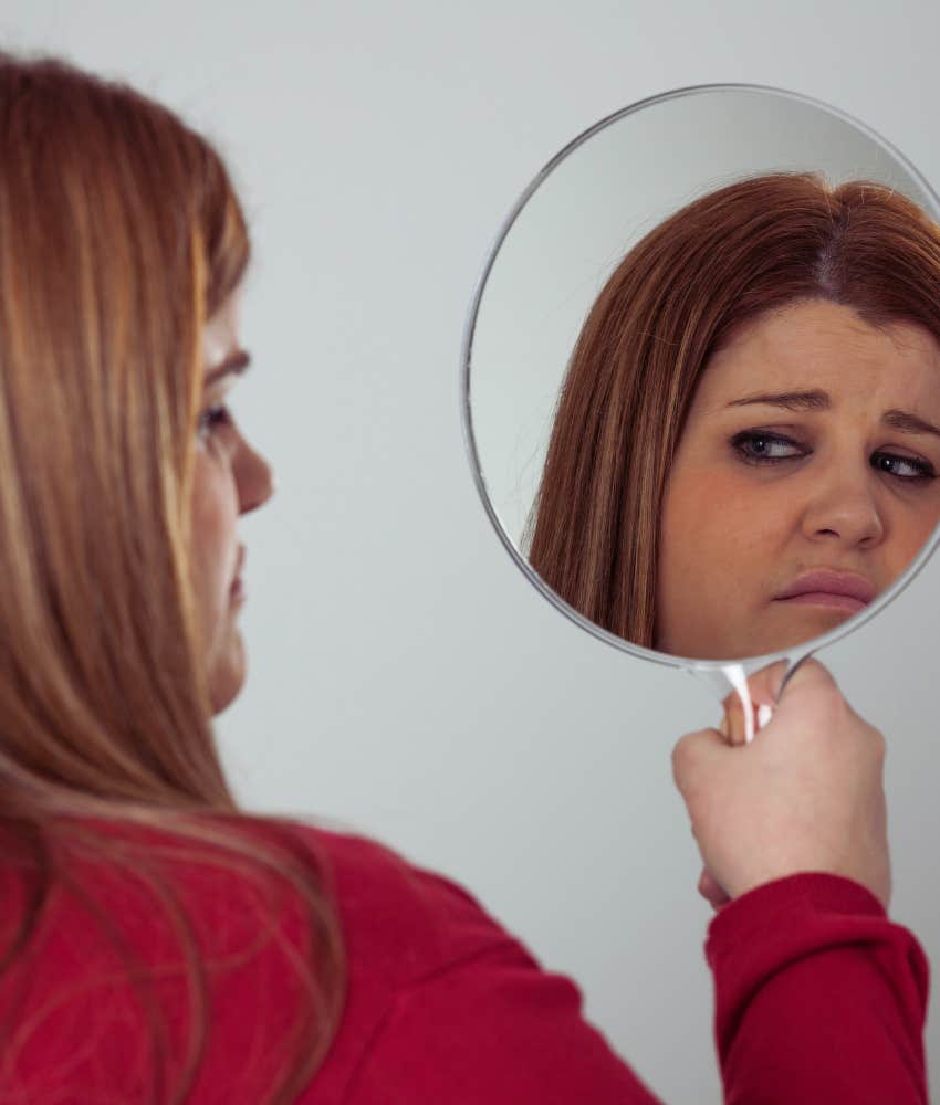 Woman critically looking in a mirror