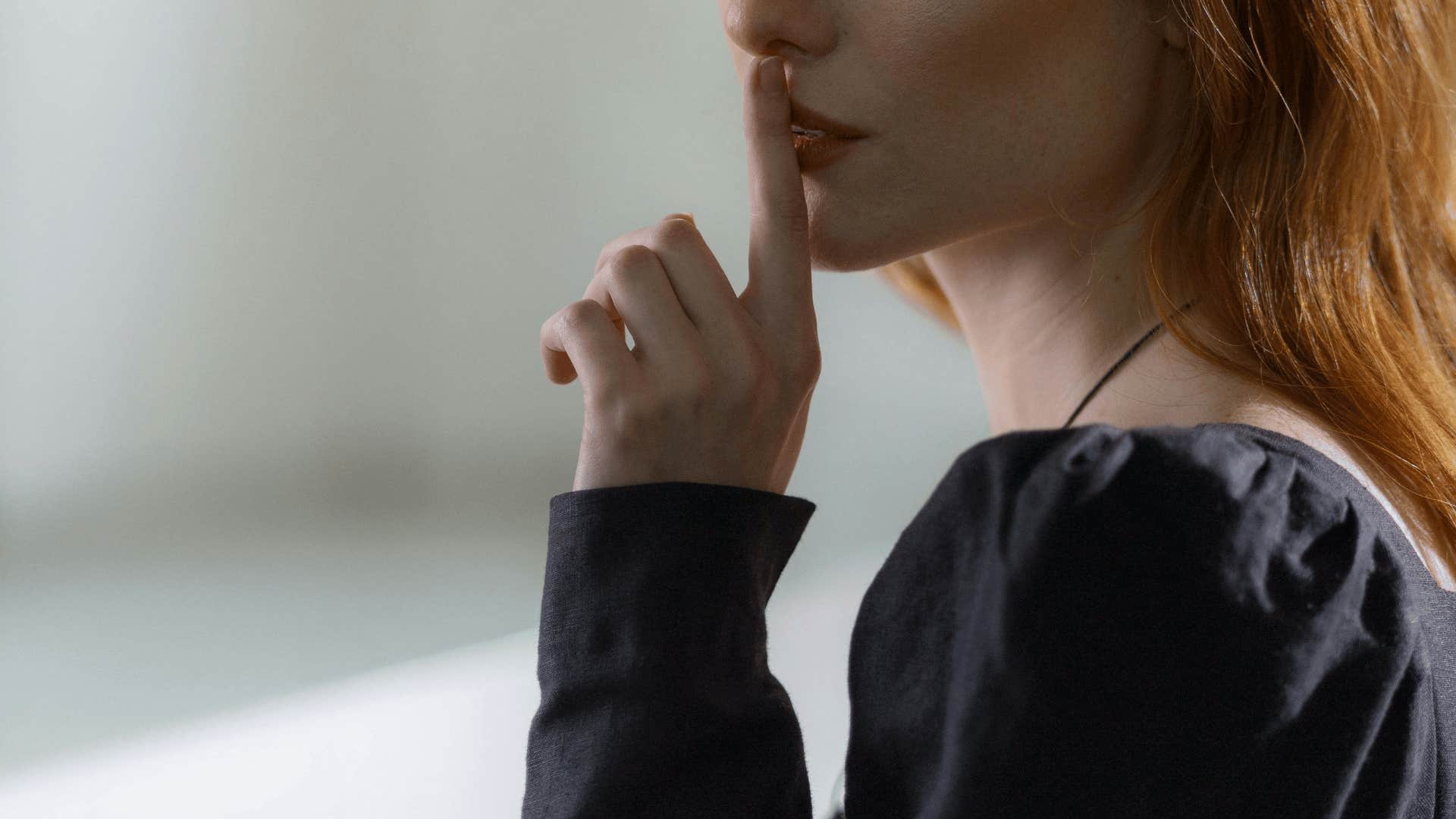 woman holding finger to lips to not introduce partner to friends