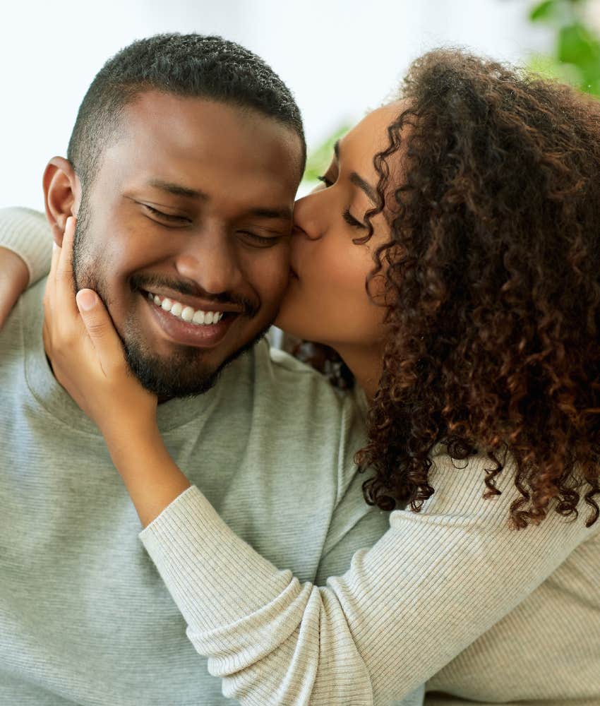 woman kissing smiling boyfriend on the cheek