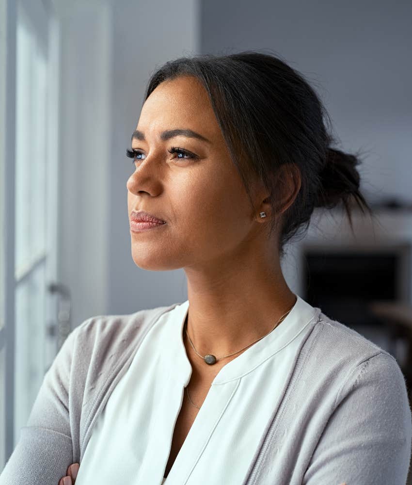 woman looking out window with a serious expression