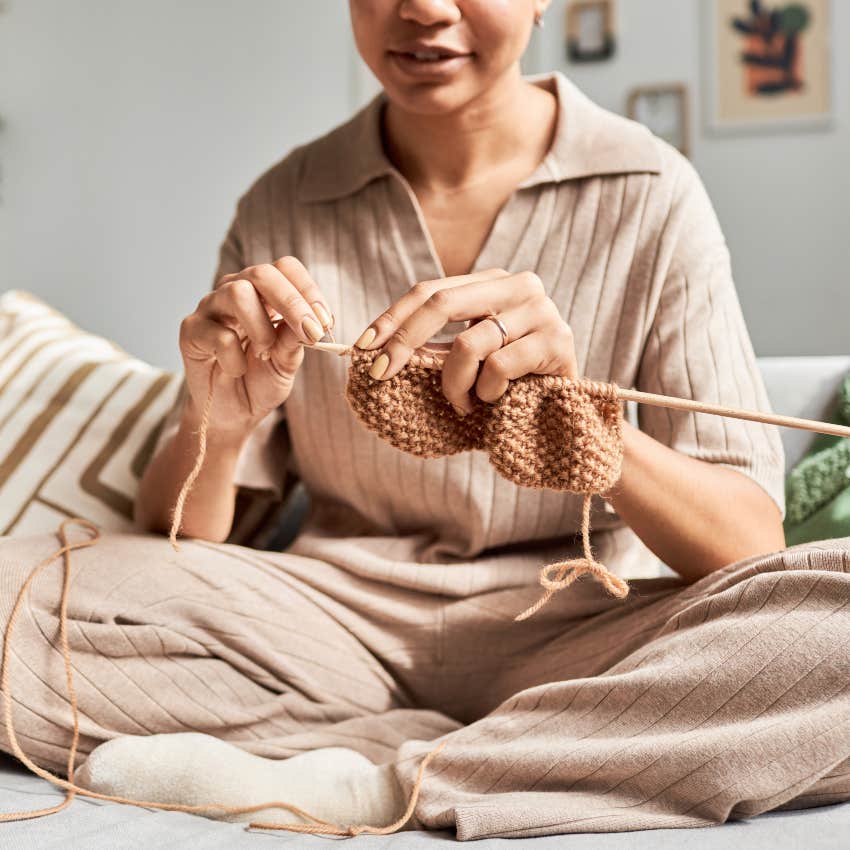 woman sitting on coach crocheting