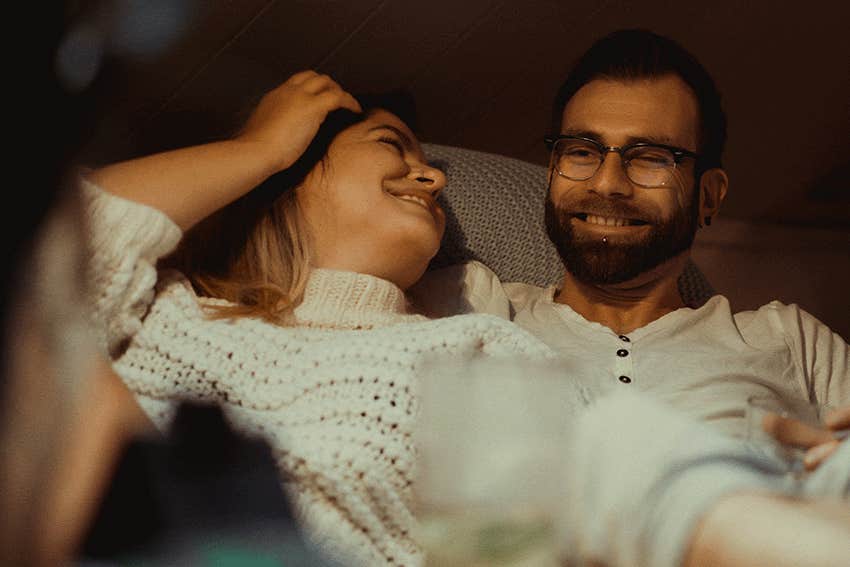 young couple in love spends a cozy evening at home on the couch with a cat.