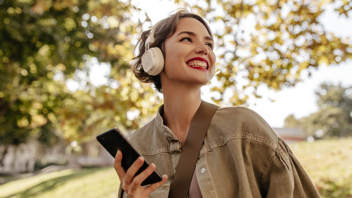 smiling woman wearing headphones walking outside