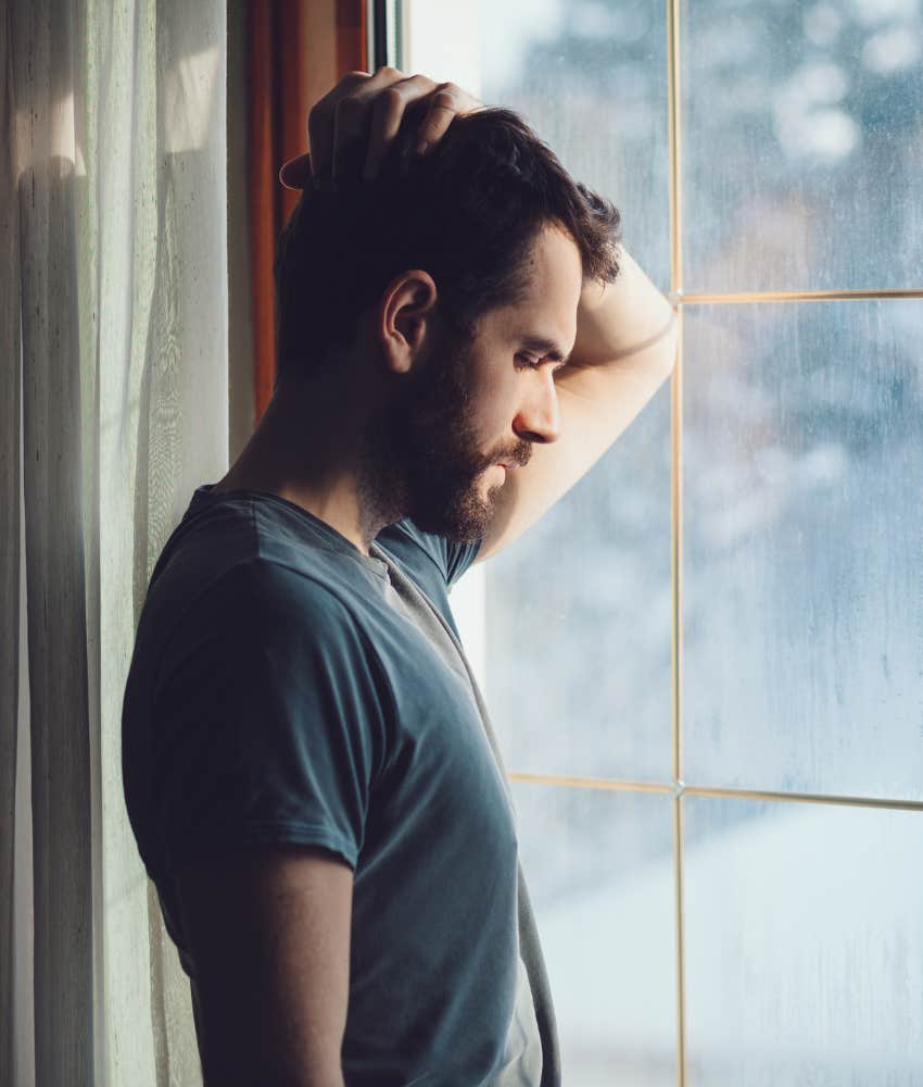 Young man sadly looking out the window