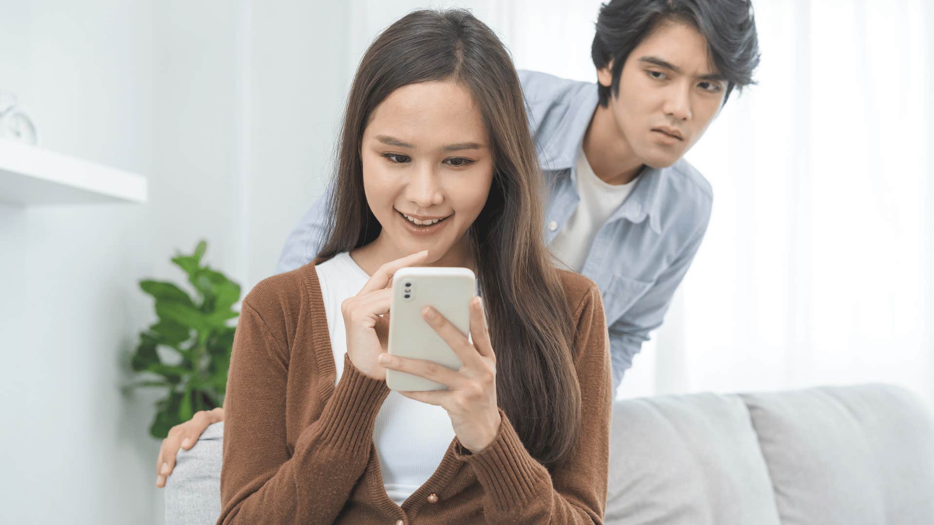 man looking over woman's shoulder on phone