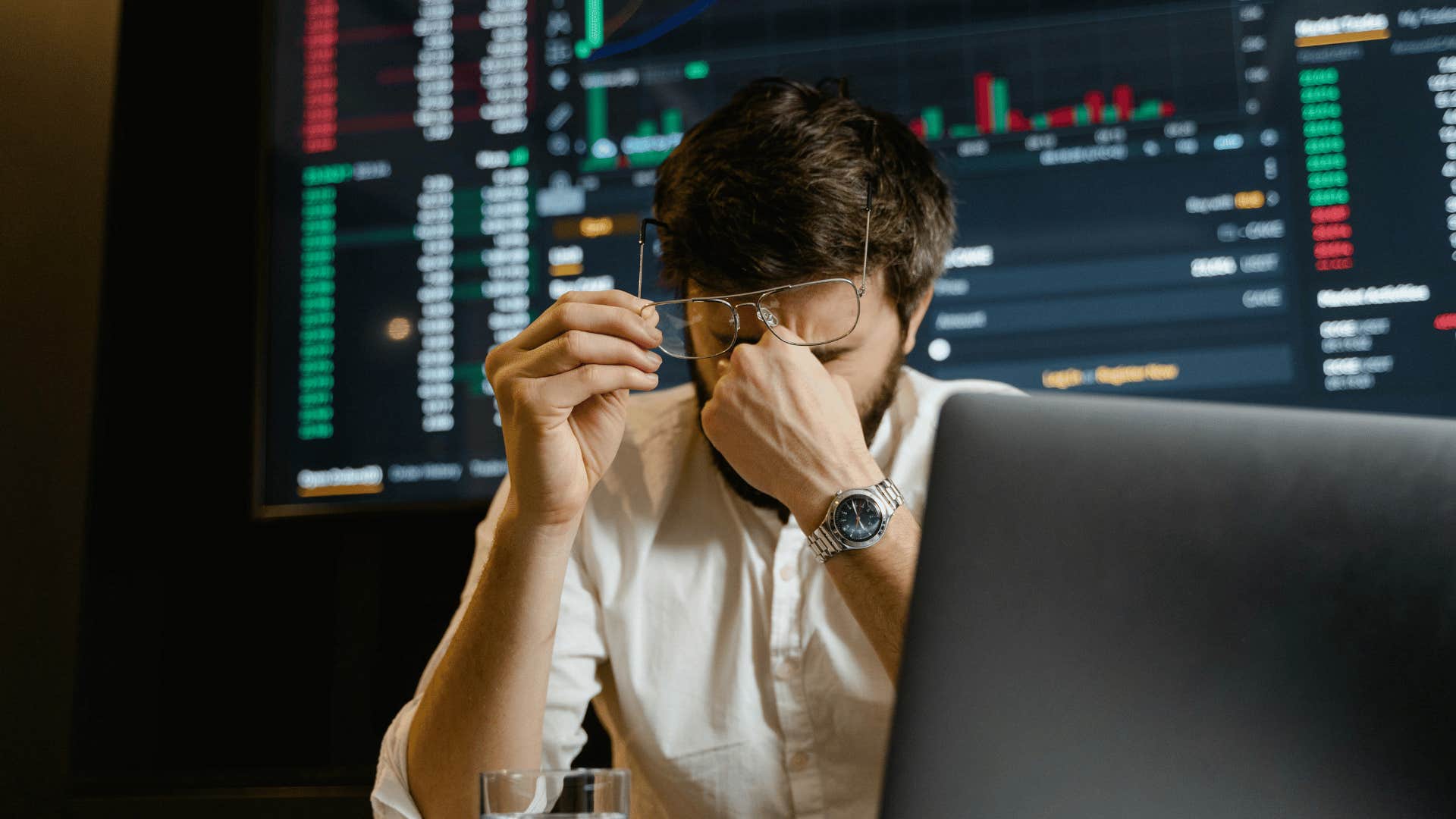 man rubbing tired eyes and keeping track of stocks