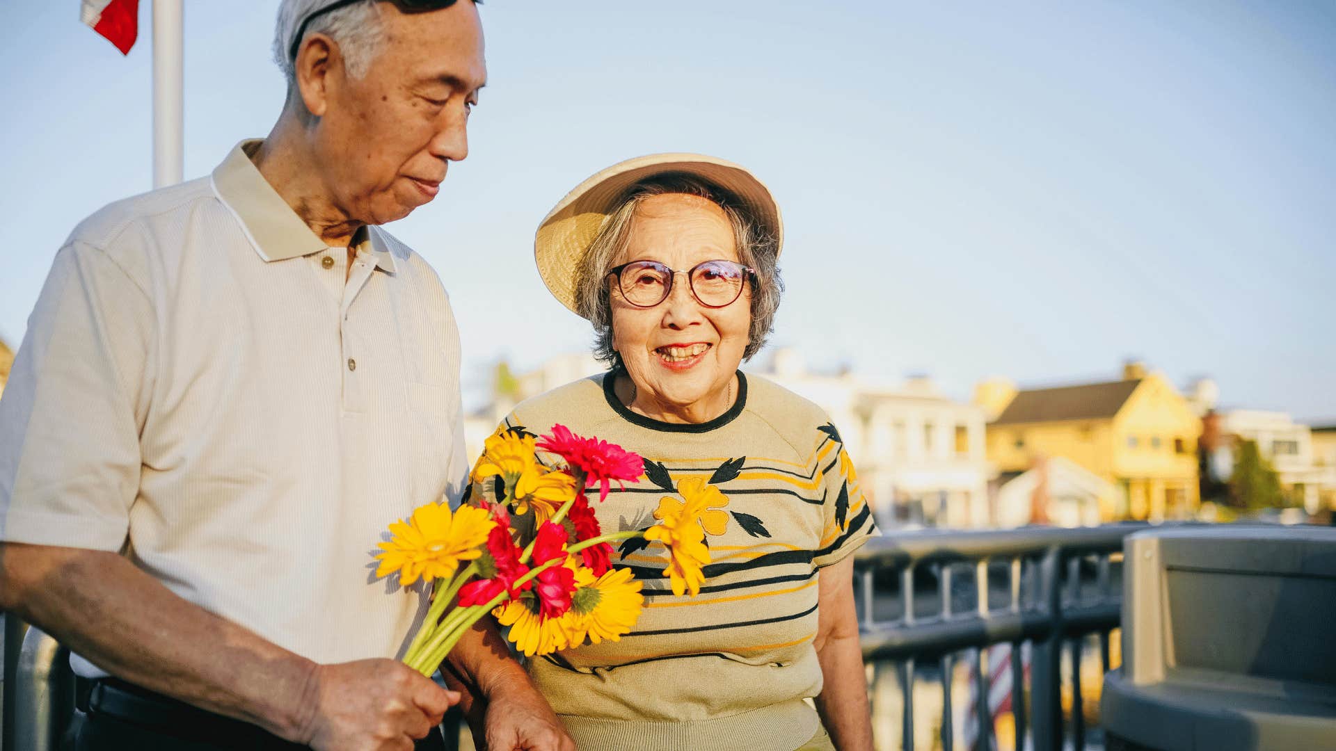 smiling elderly woman and elderly man holding flowers