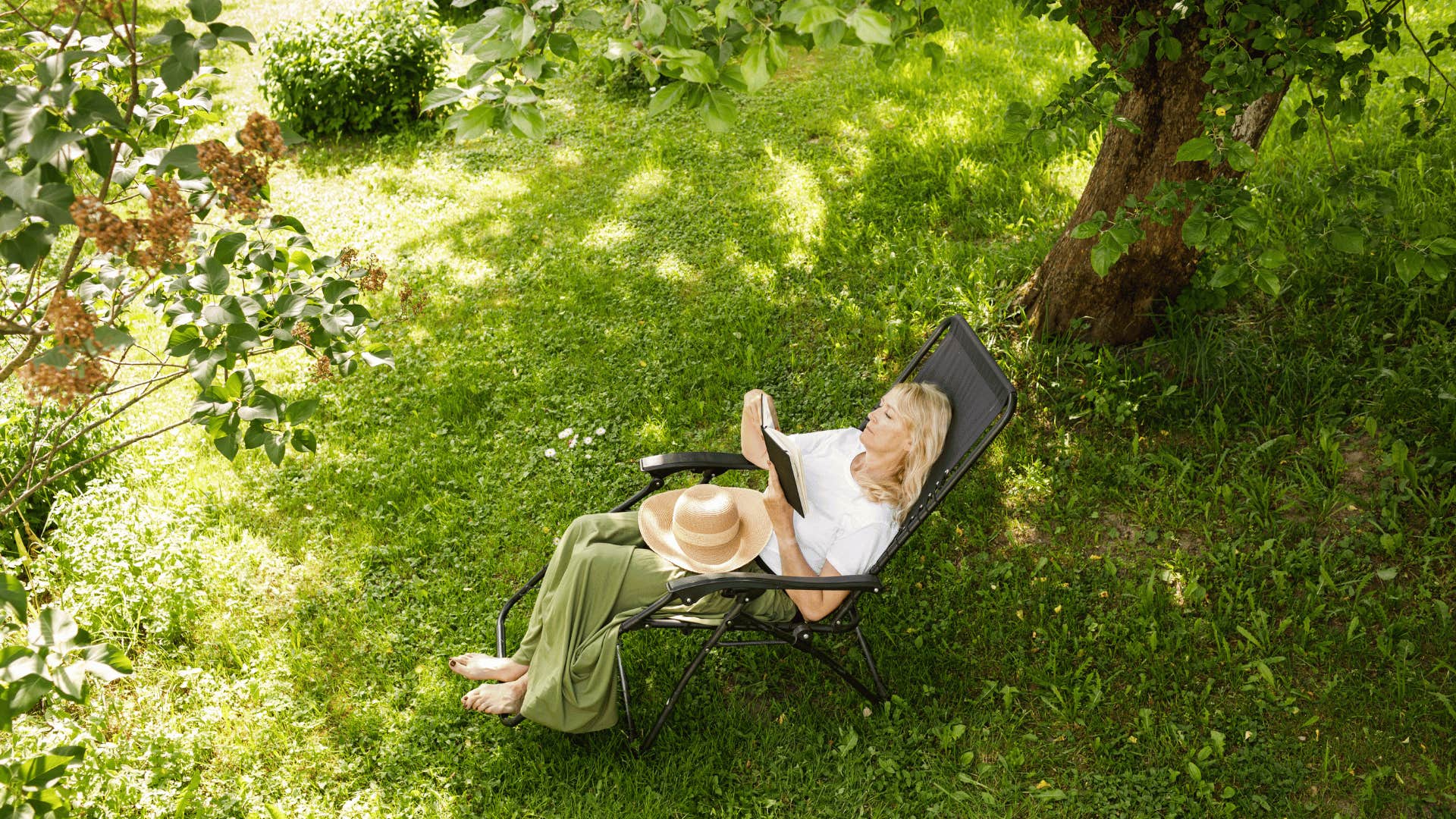 woman sitting in lawn chair outdoors and reading