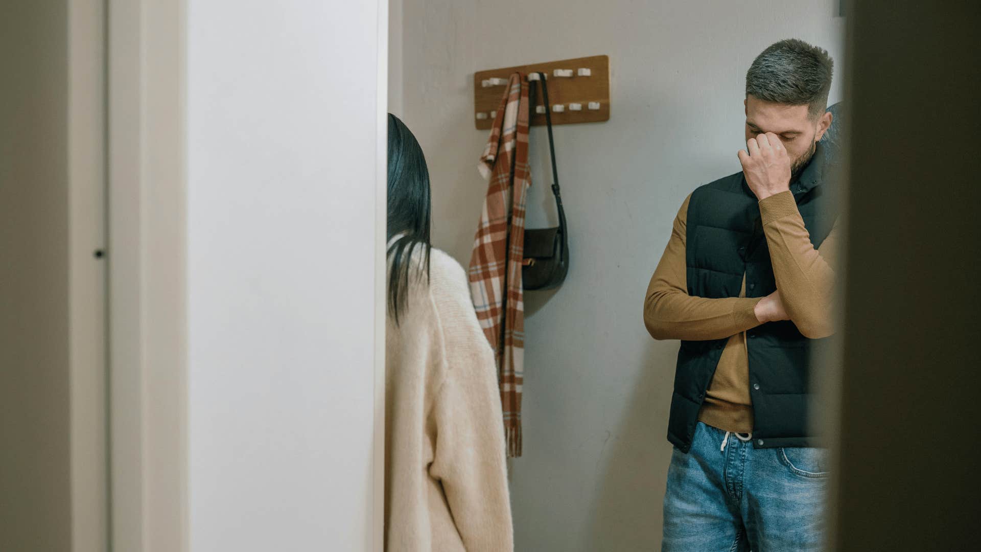 couple standing in hallway and man pinching his nose