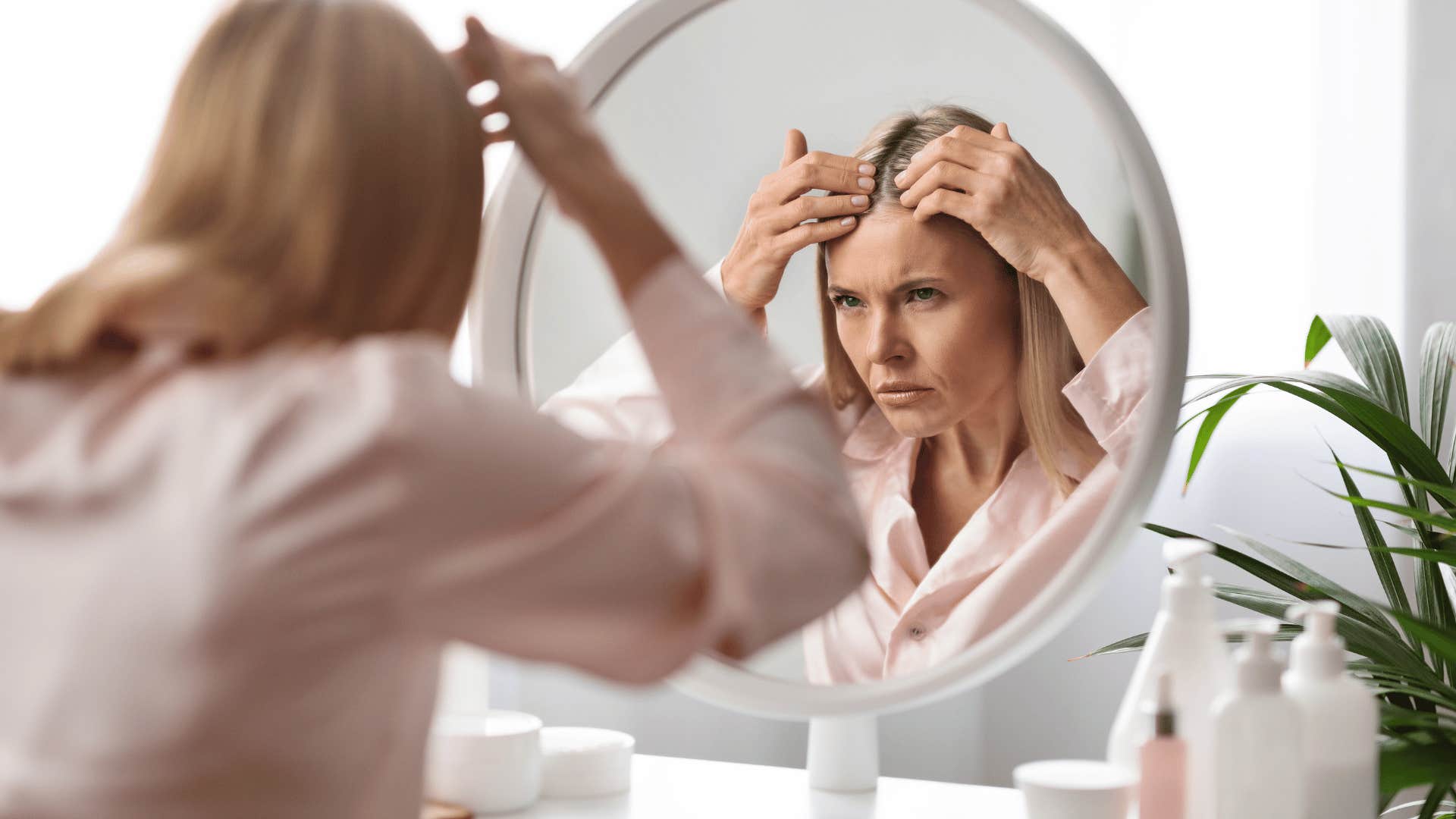 discouraged woman looking at her reflection in mirror