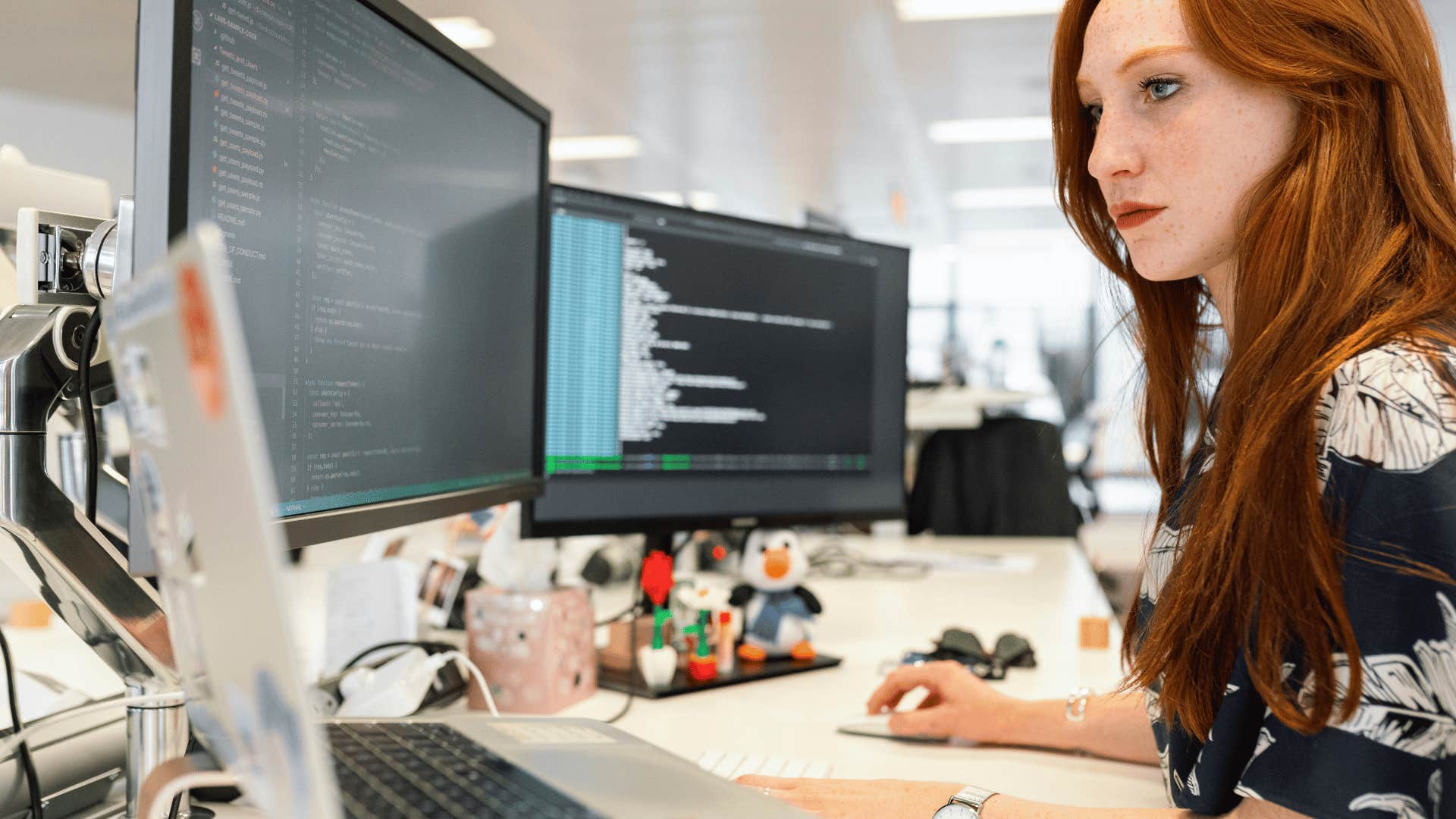 young woman working on three screens