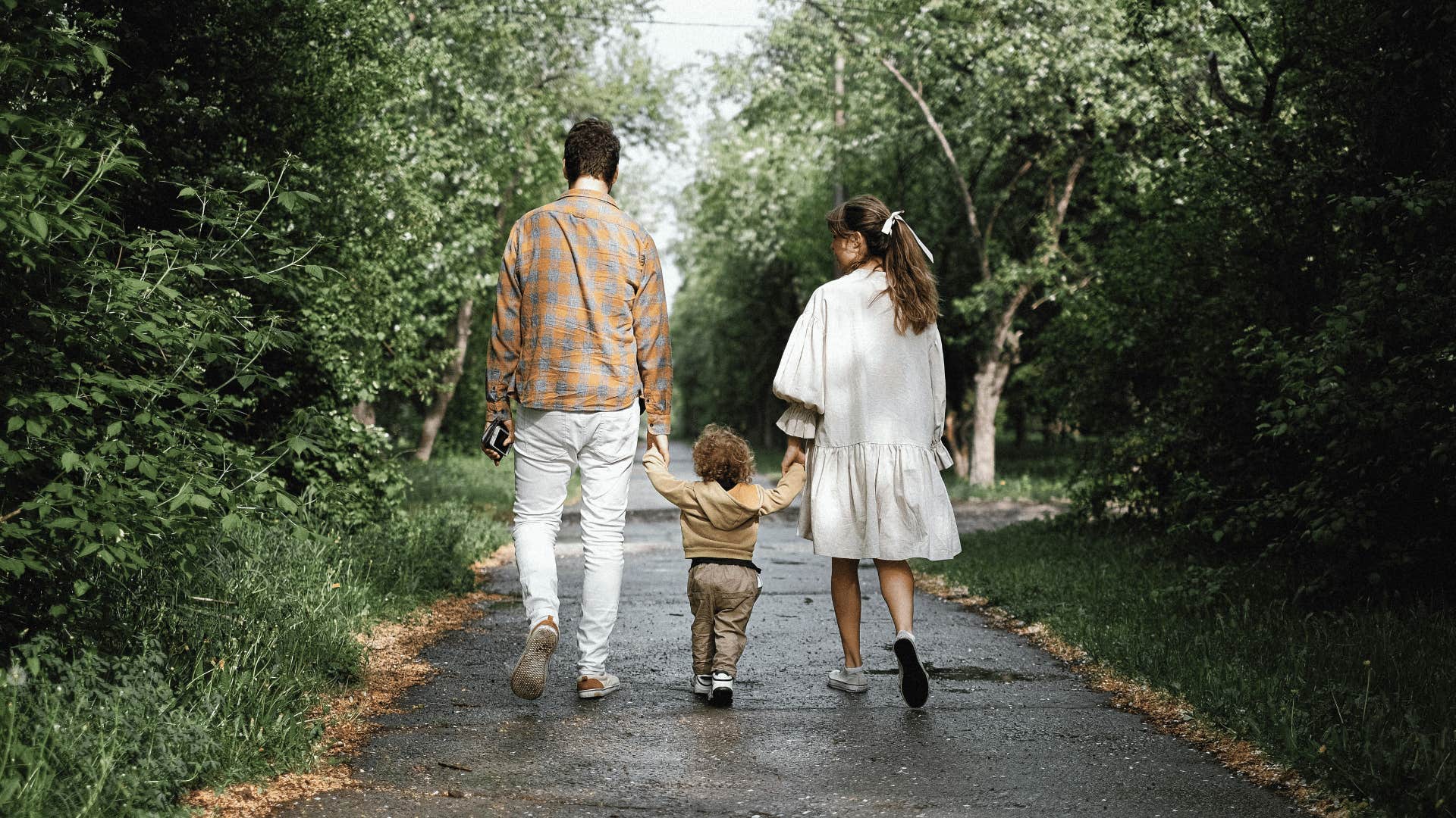 couple holding toddler's hands while walking