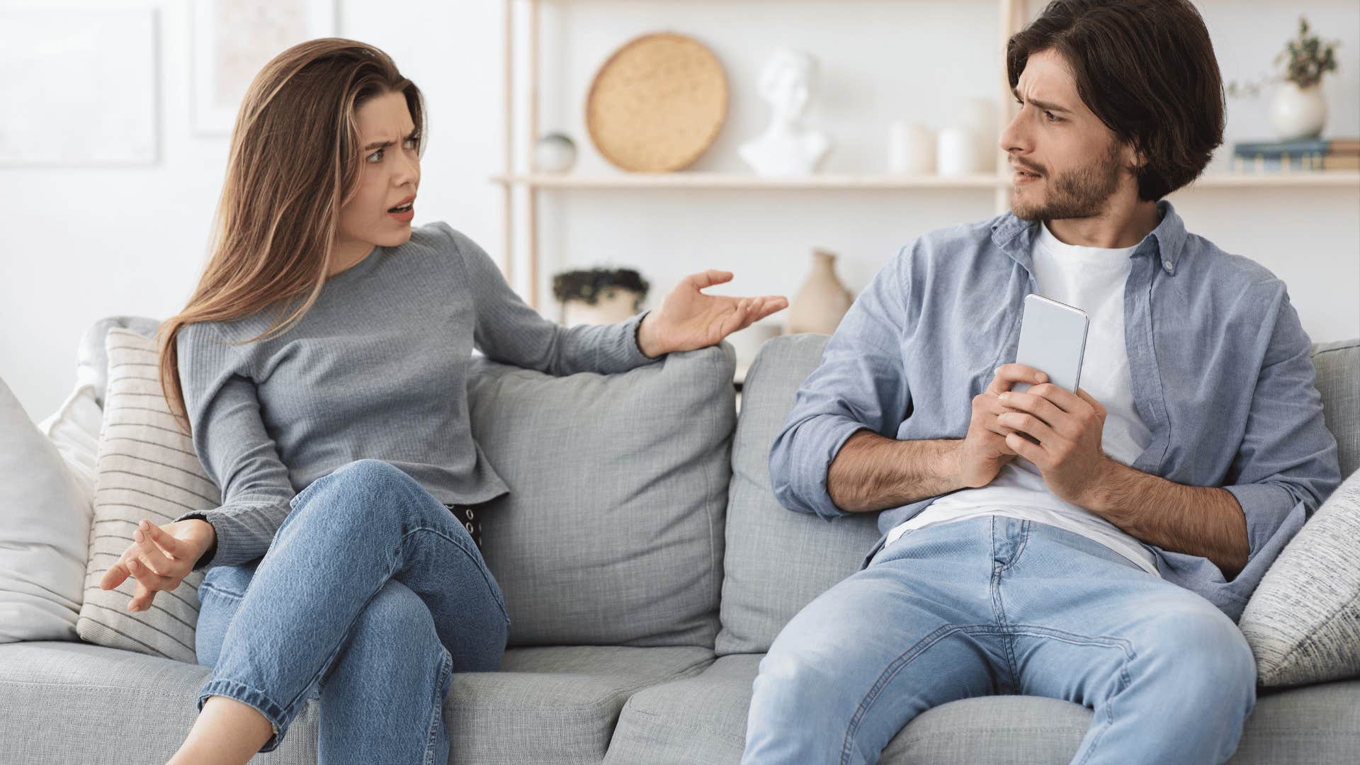 man hiding phone screen from upset woman