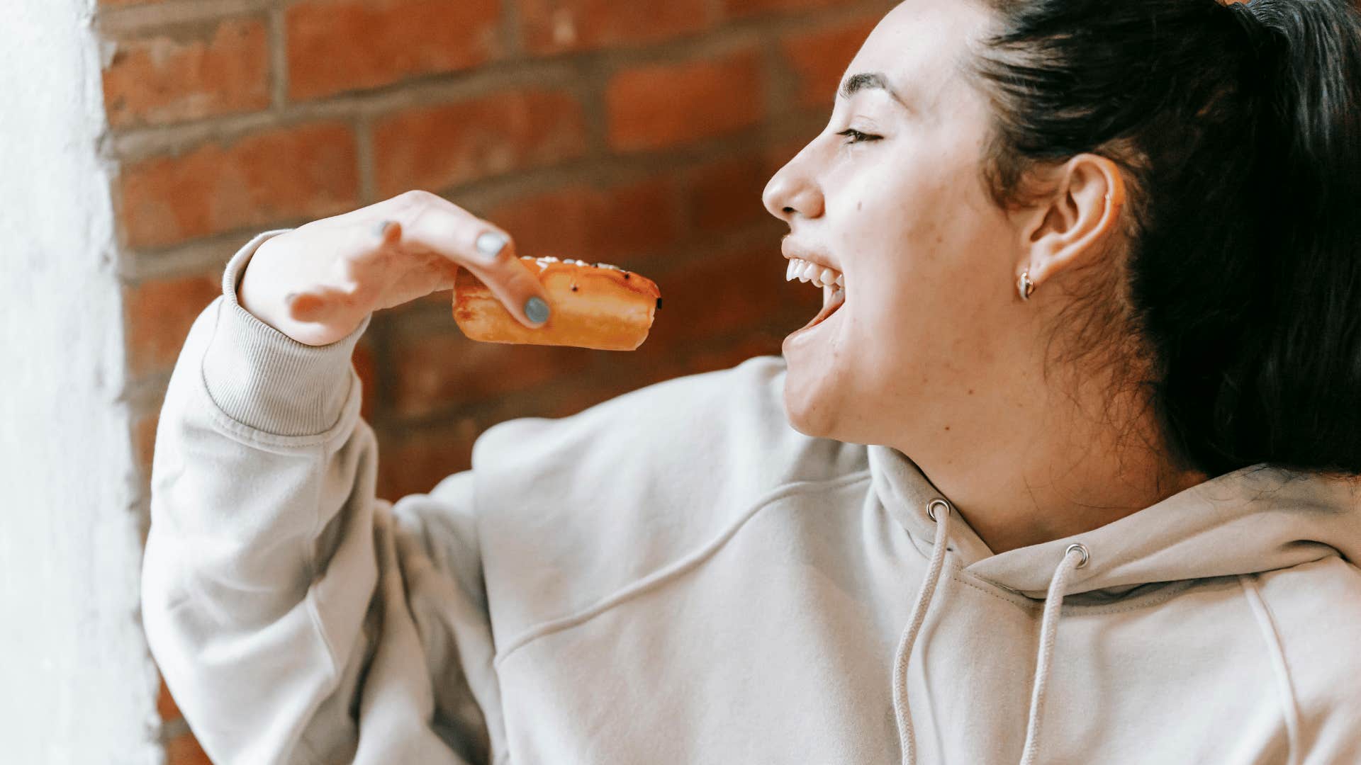 smiling woman holding donut close to mouth