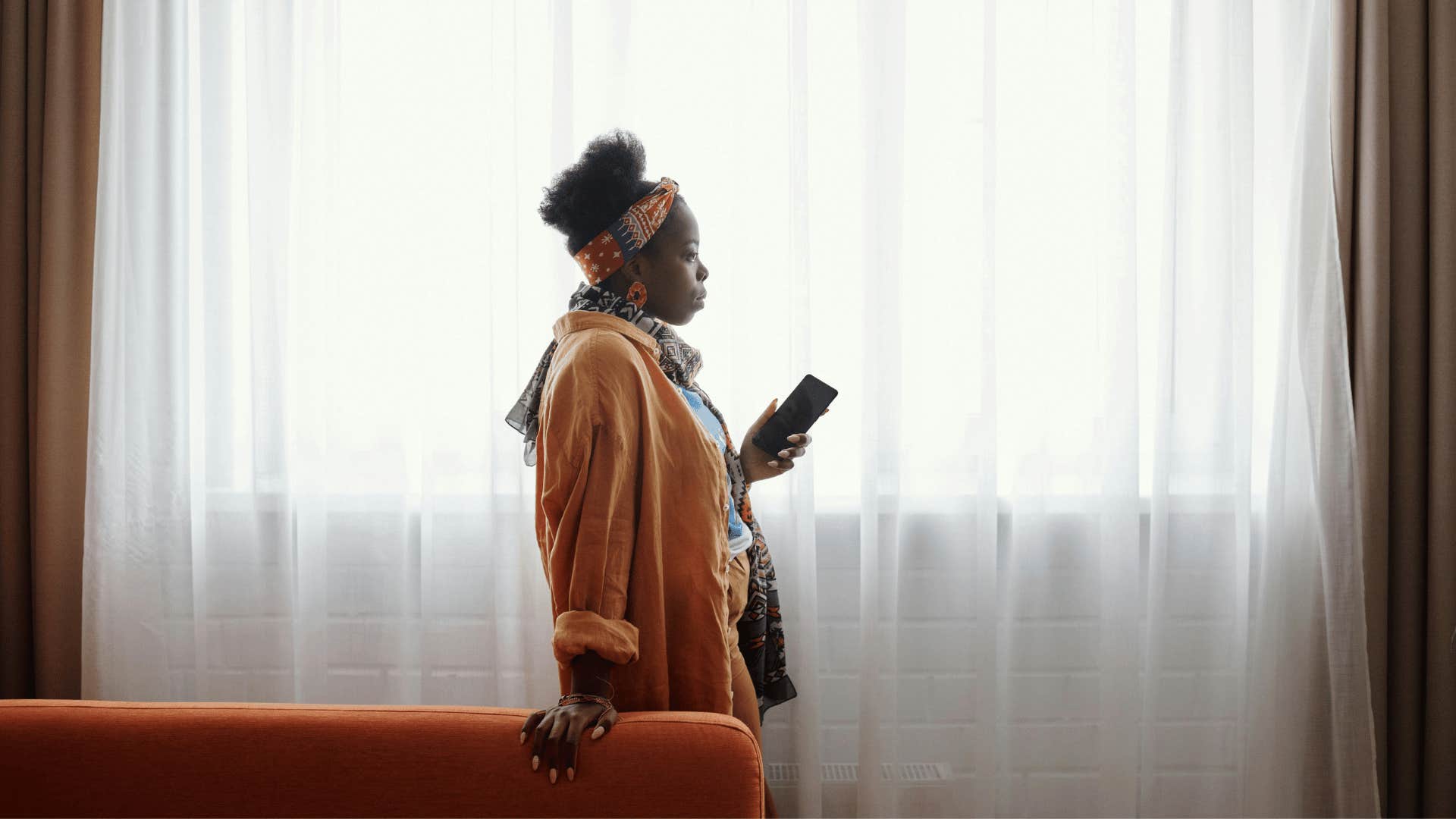 woman holding phone while staring into space