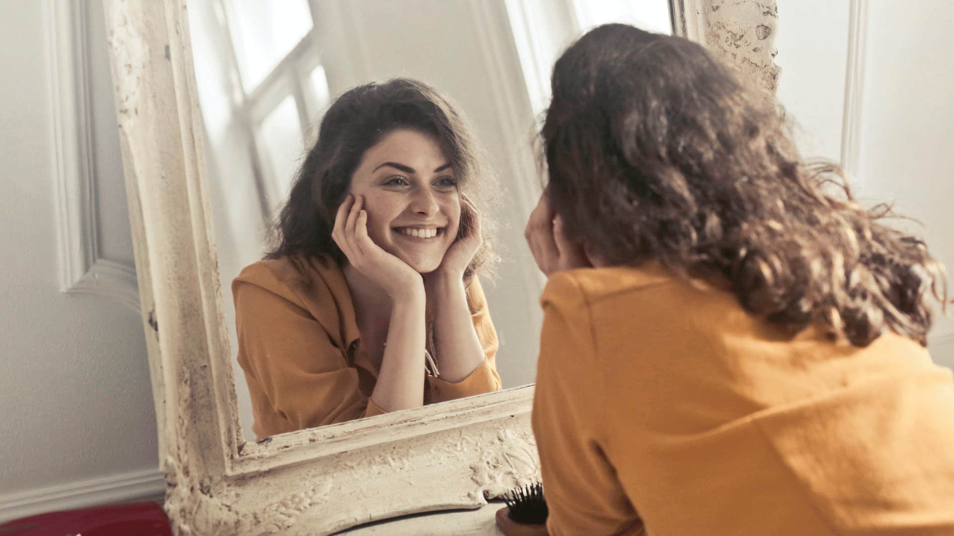 woman smiling into a mirror