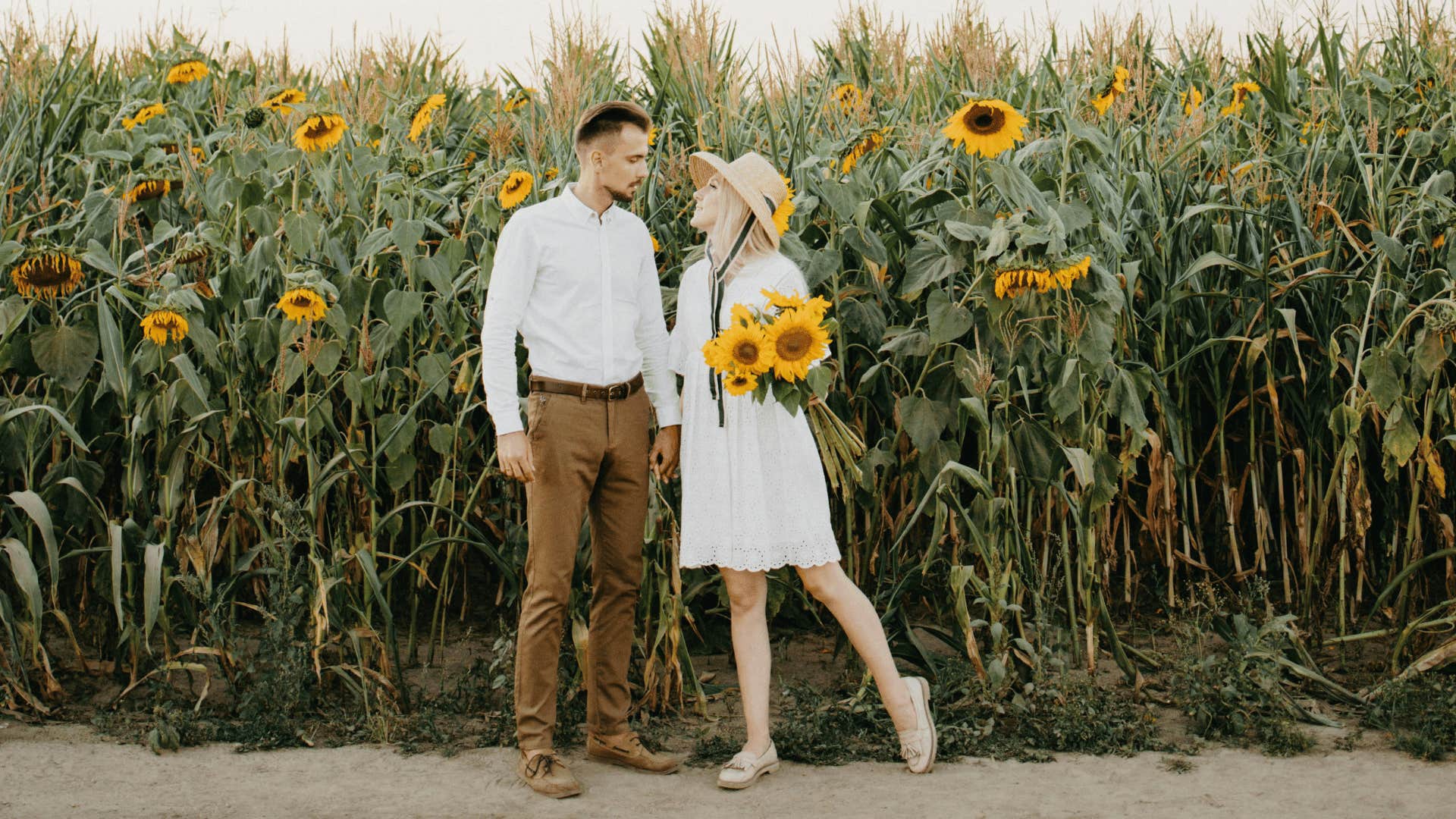 couple standing outside of sunflower field