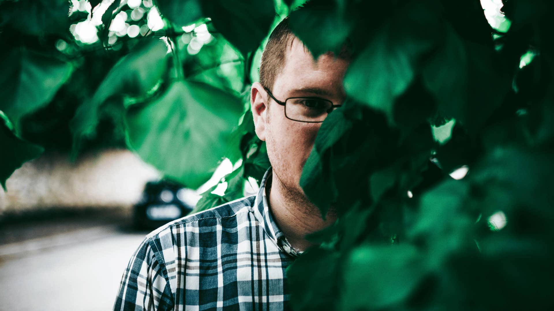 mysterious man standing behind foliage