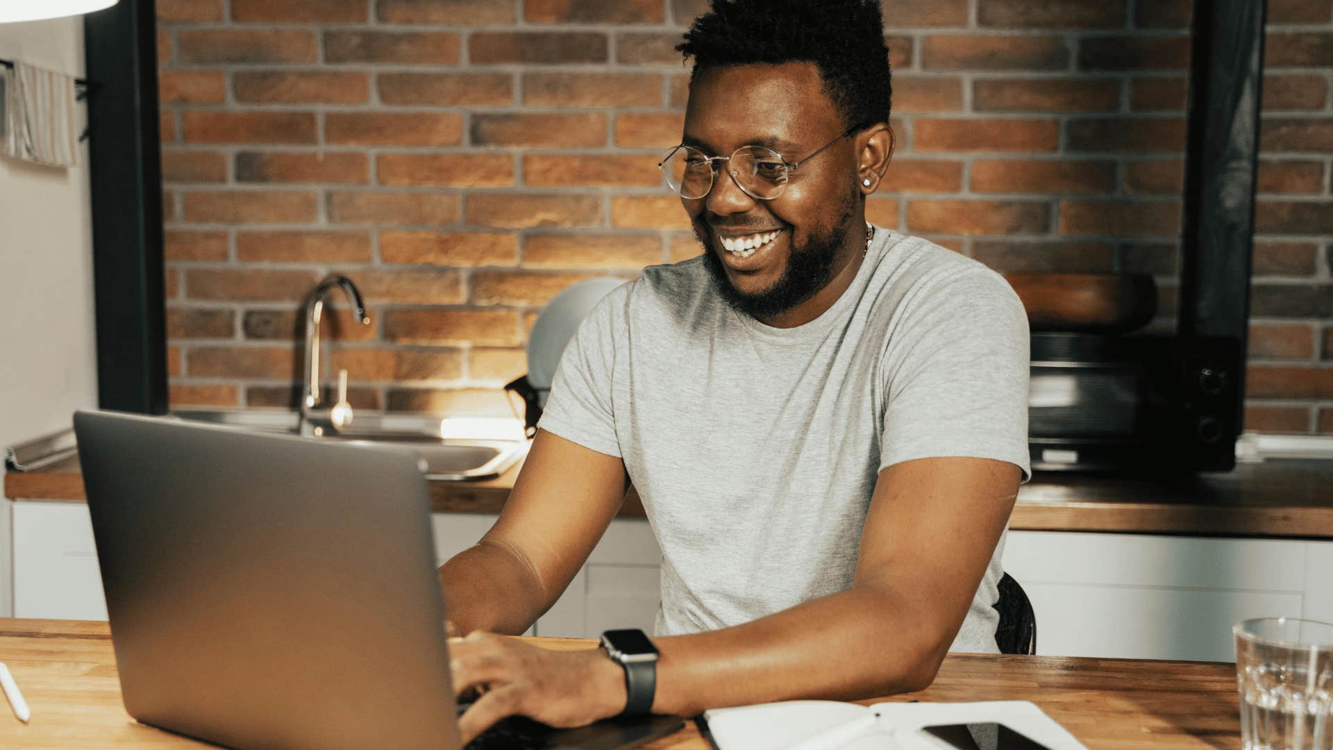 smiling man typing on laptop