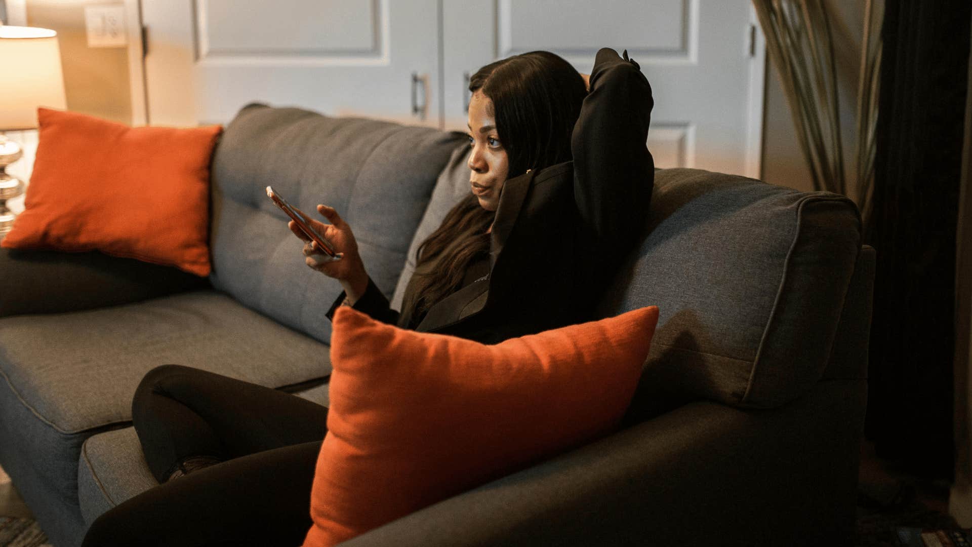 woman holding phone while sitting on couch