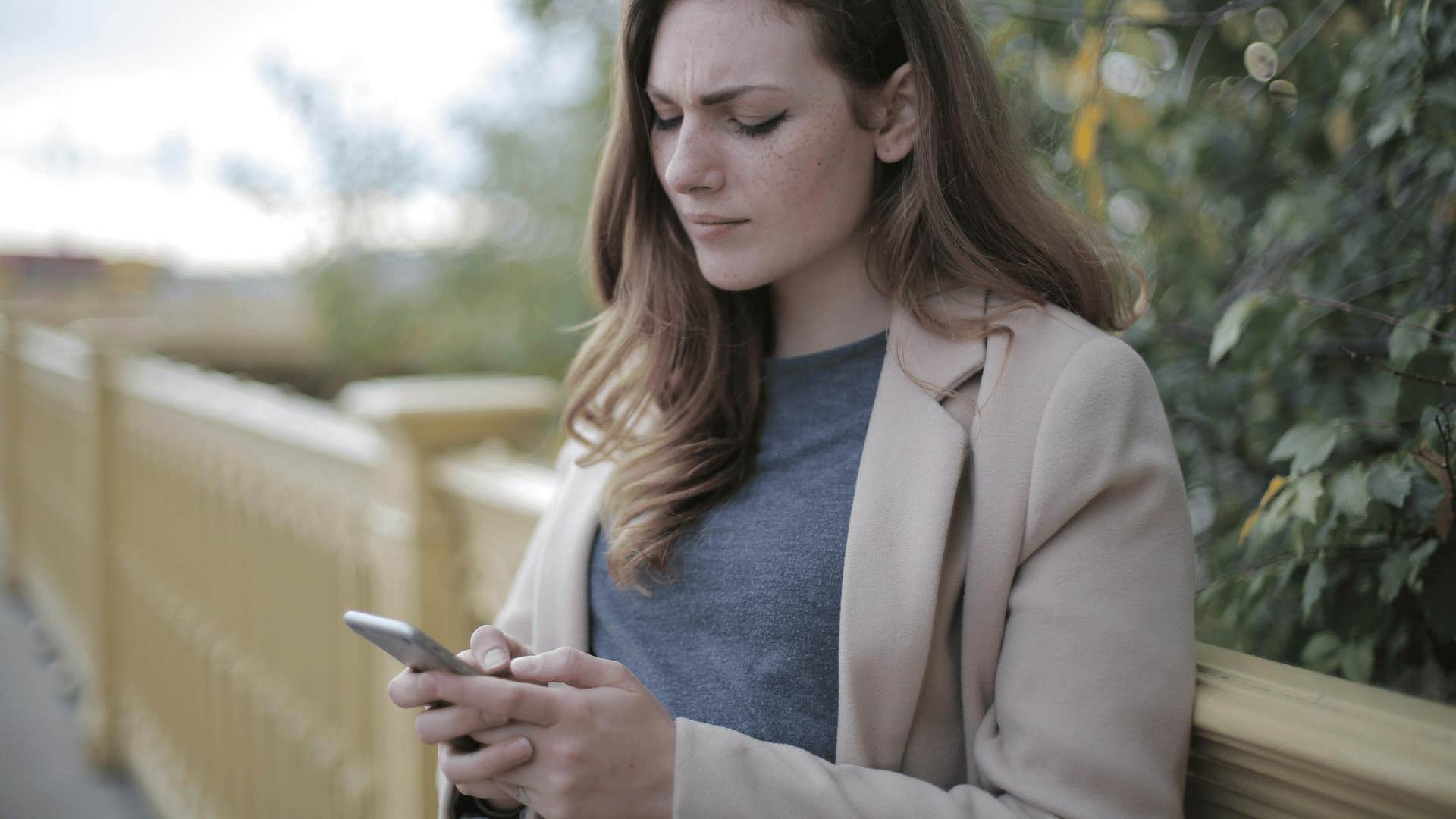 young woman with furrowed brows looking down at phone