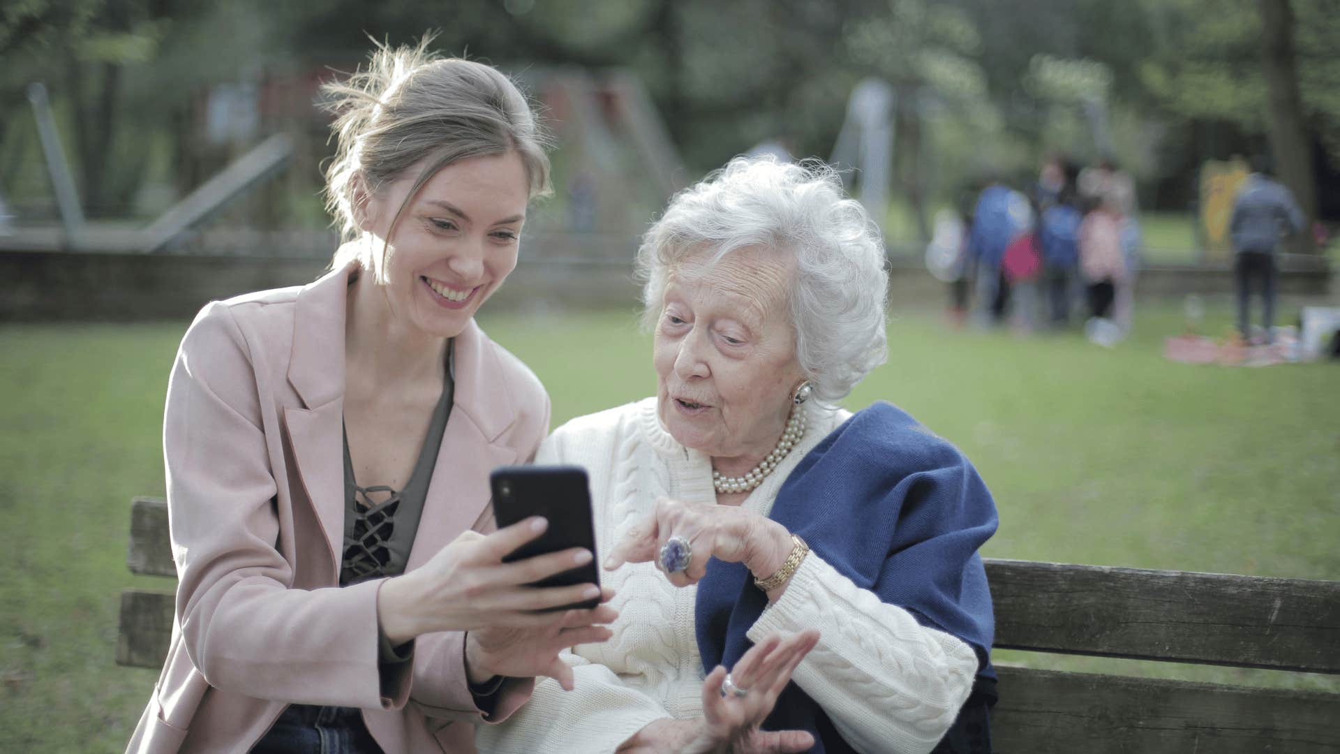 young woman teaching older woman how to utilize phone