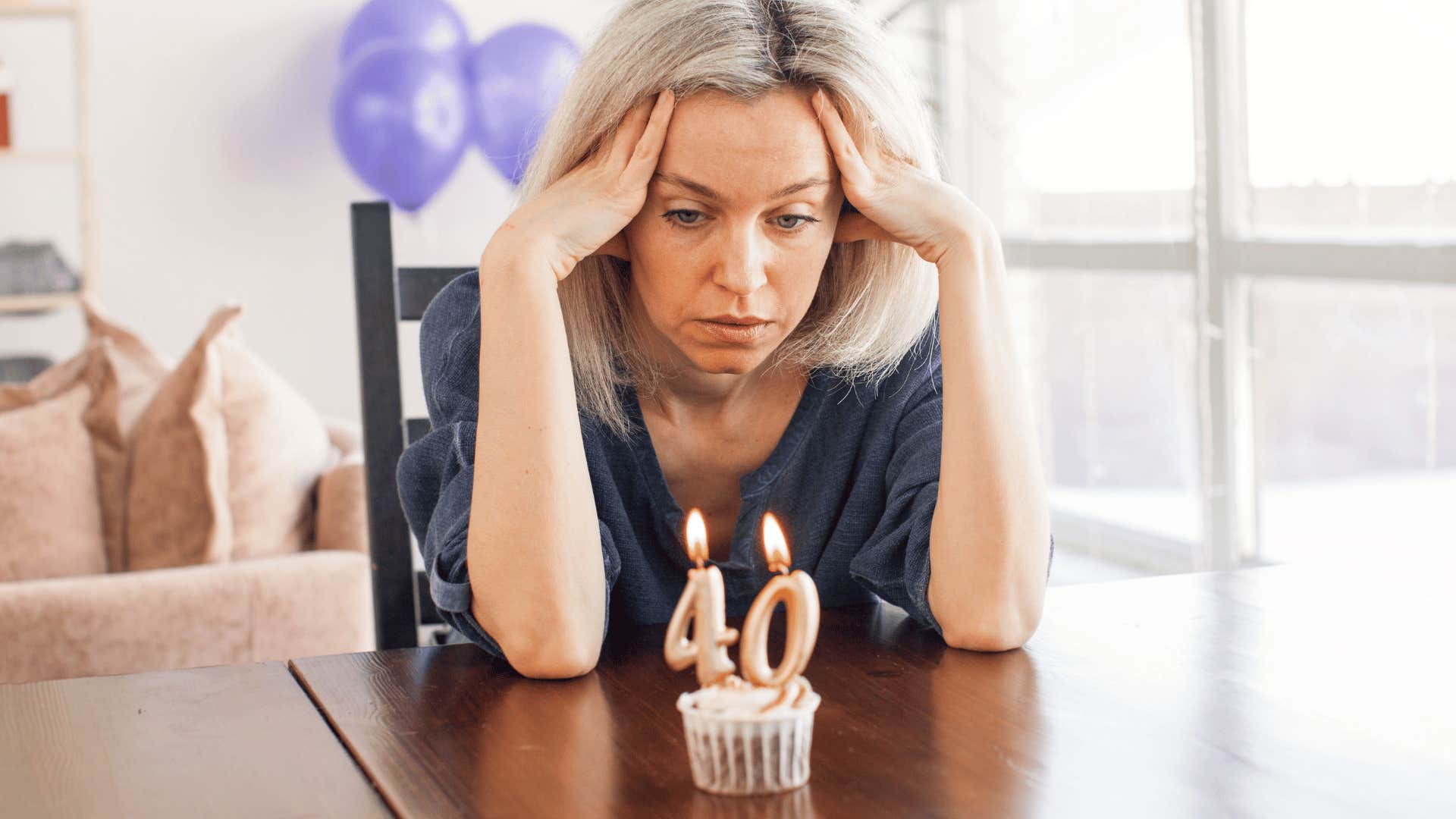 discouraged woman staring at birthday cupcake candles