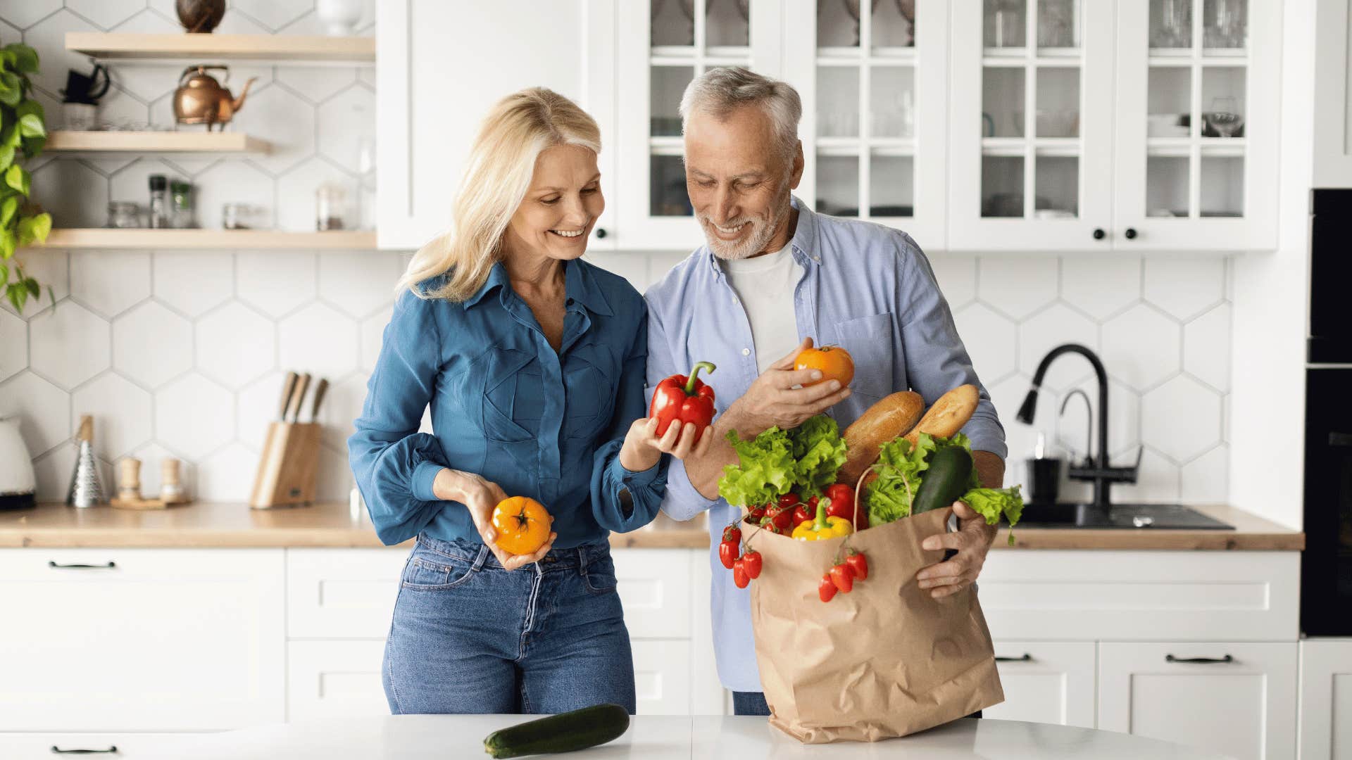 happy older couple unpacking fresh groceries