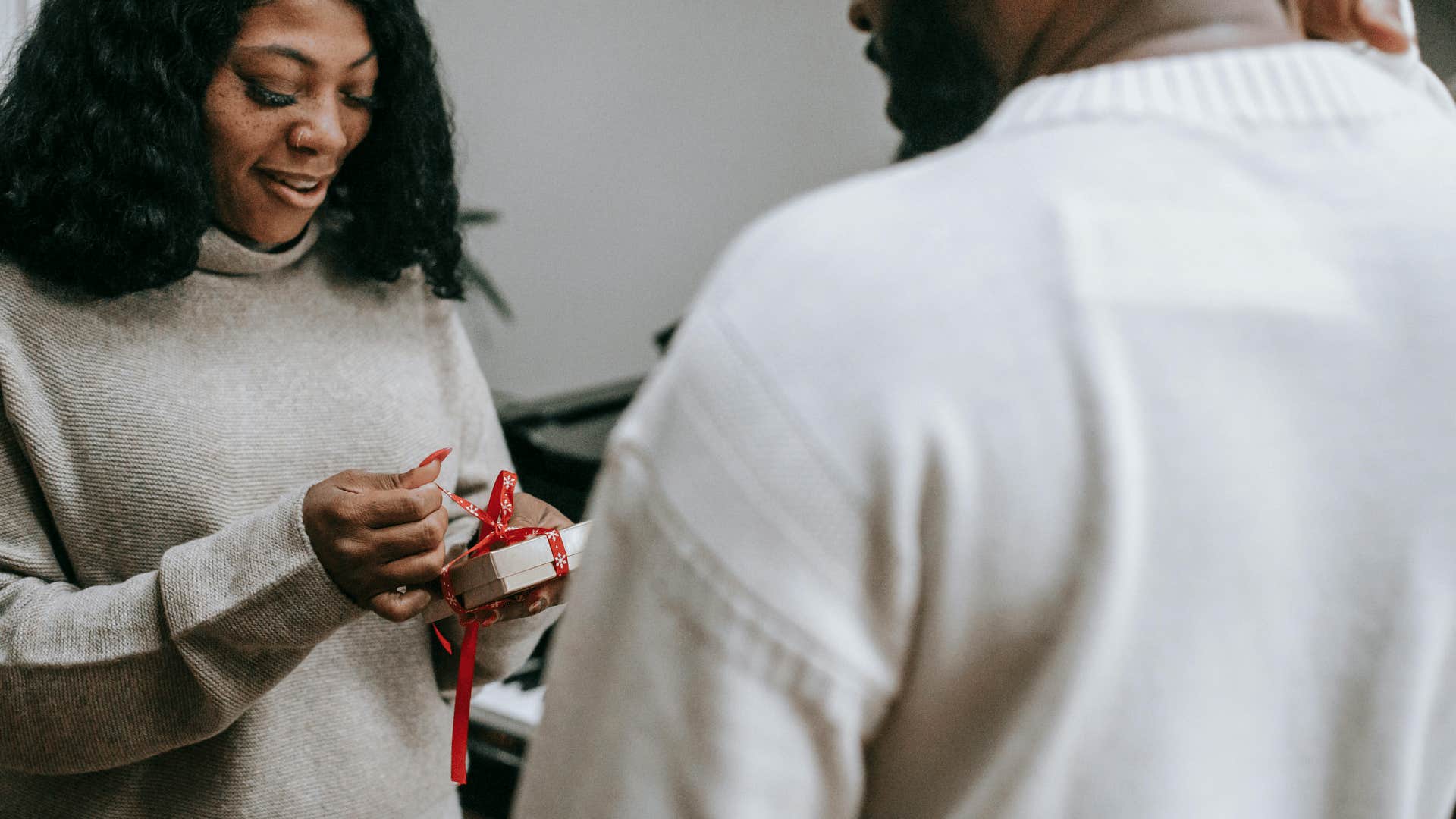 woman untying bow on gift from man