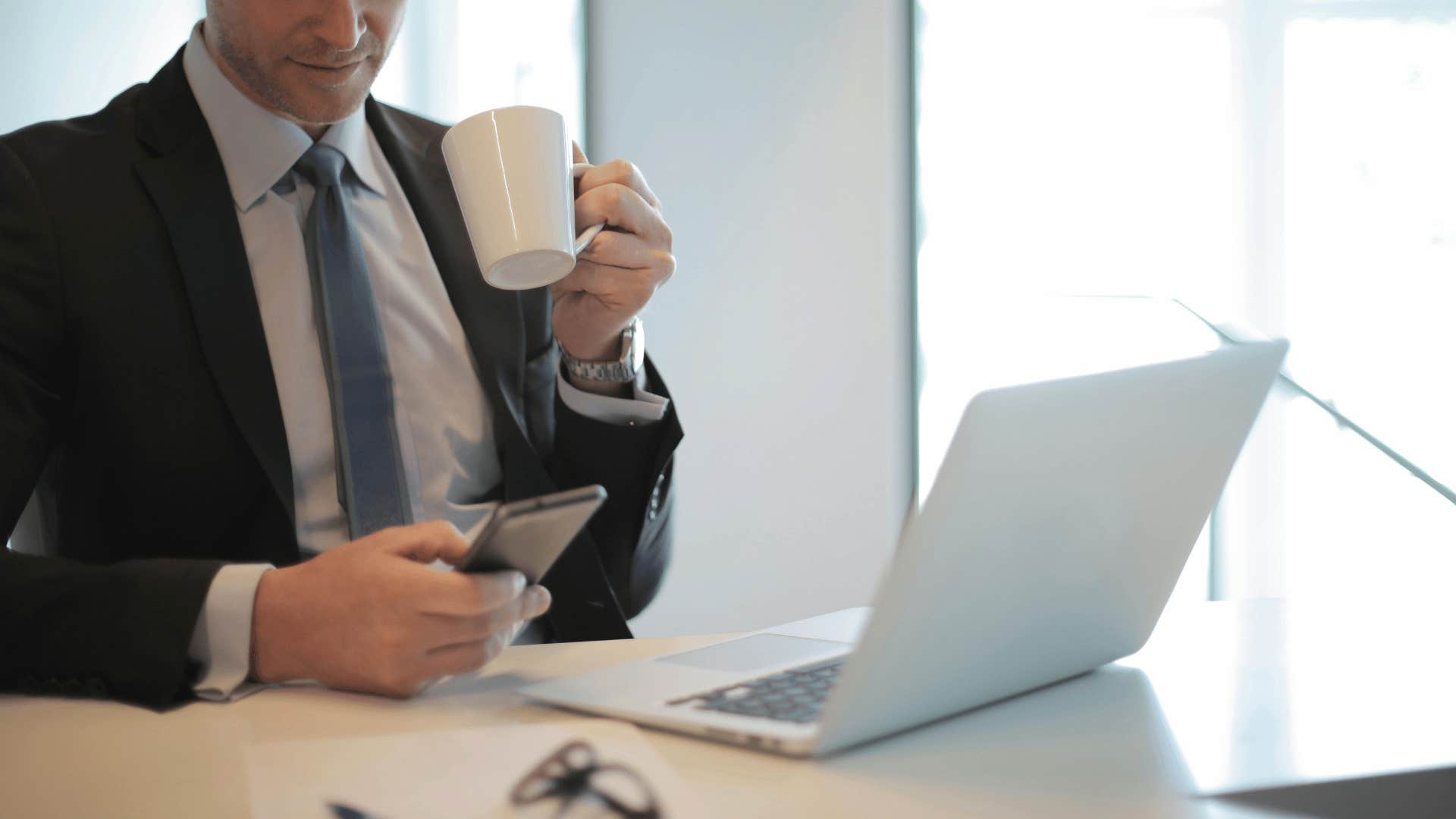 Businessman holding a mug and a mobile phone