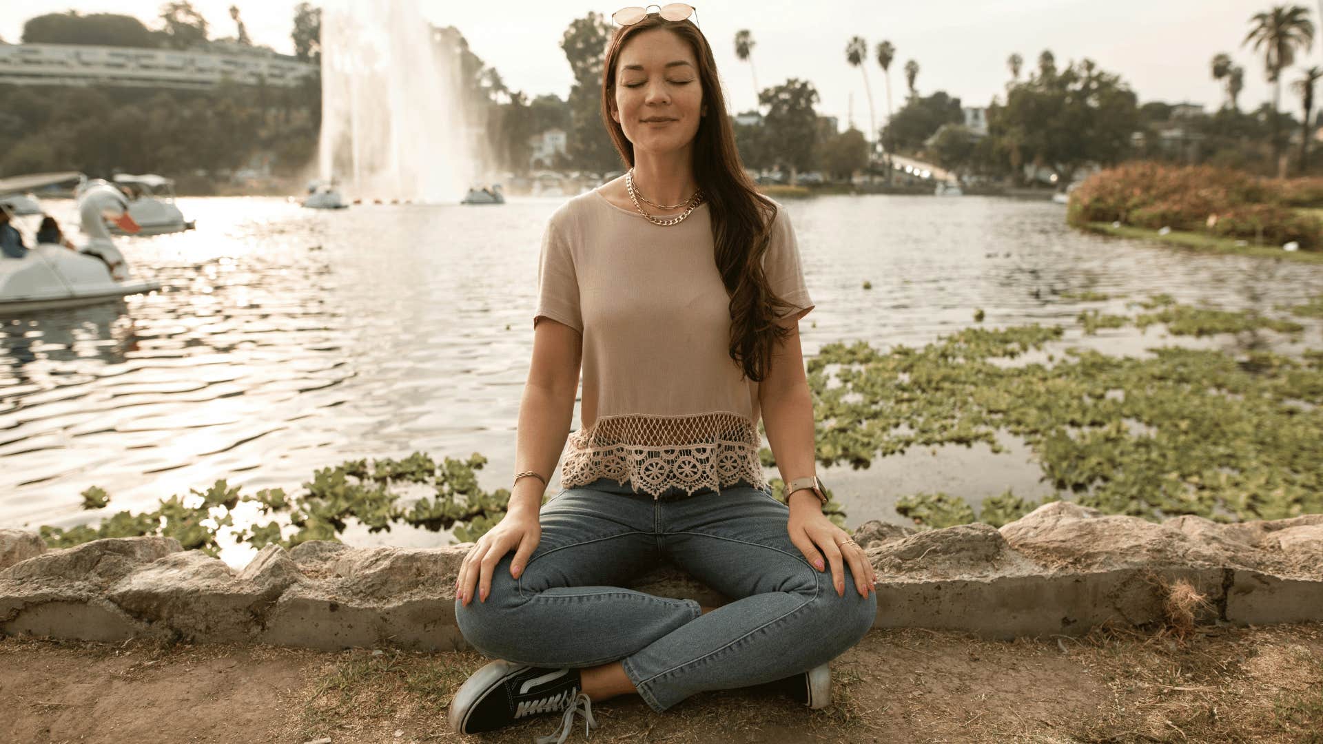 woman meditating by lake