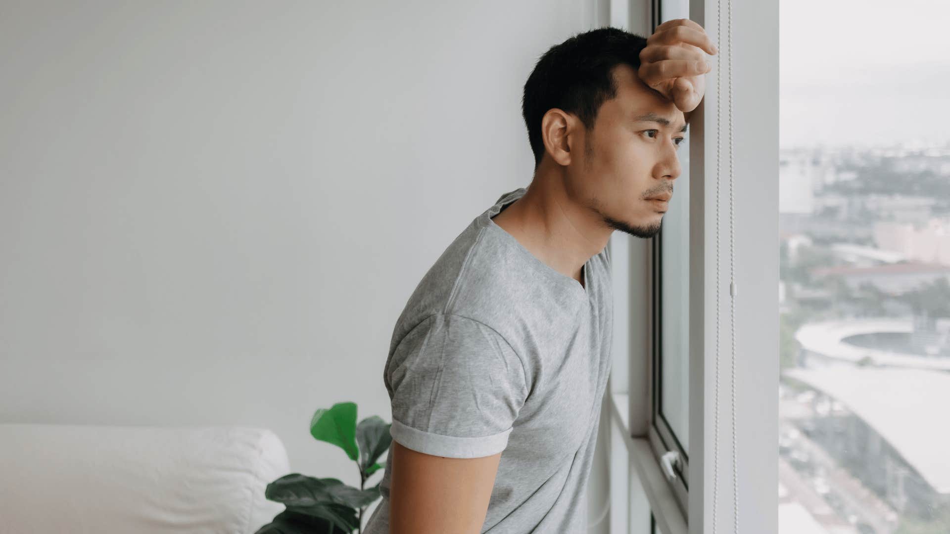 young man looking outside through window